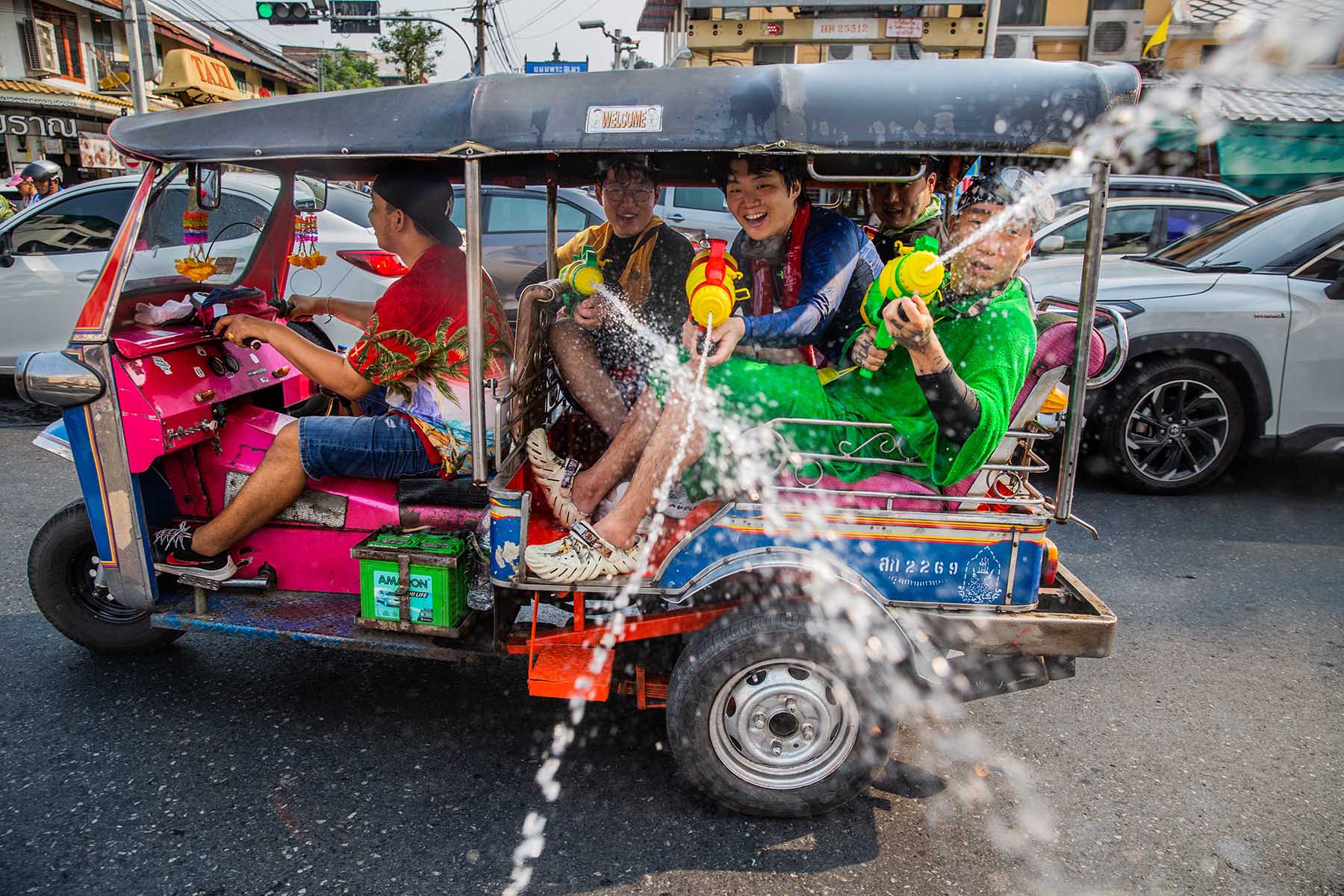 People on a tuk-tuk in Bangkok shooting others on the street with water guns during the Songkran Festival in Thailand