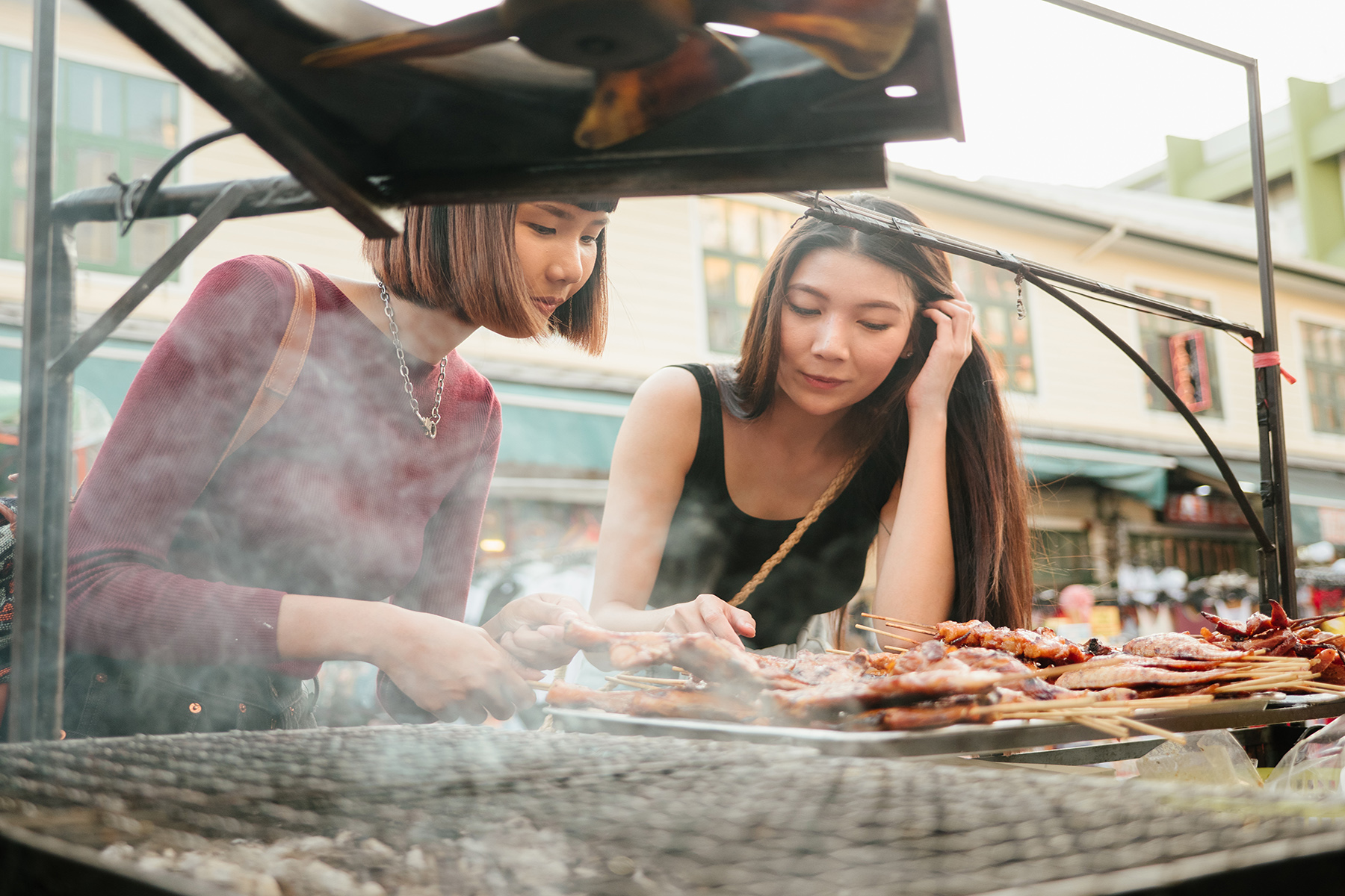 Two women tasting street food in Thailand