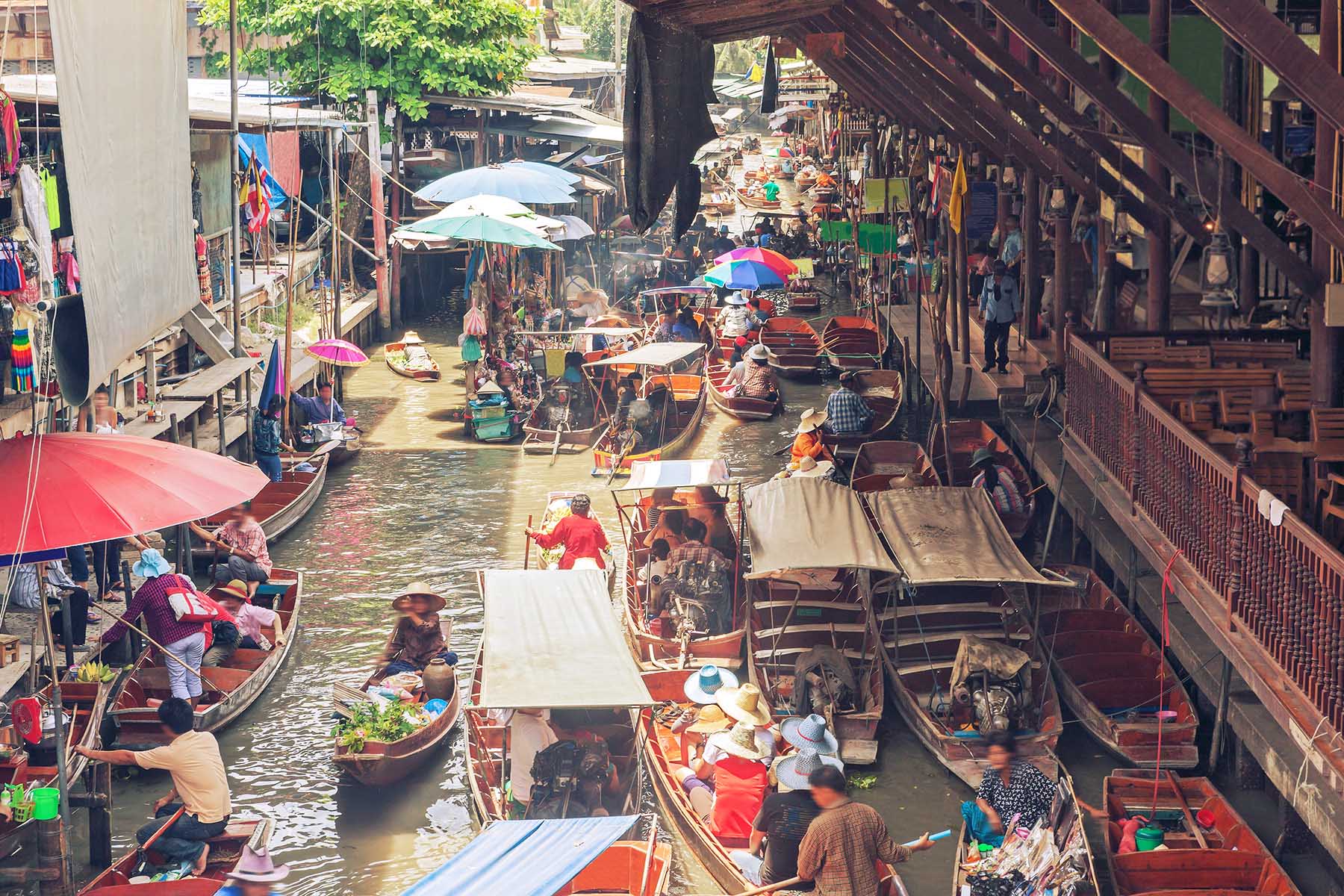 Loads of people visiting and traveling through a floating market in Bangkok, Thailand.