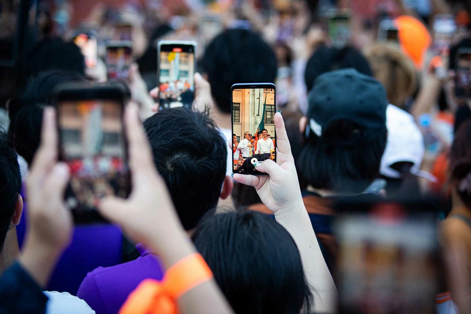 A sea of mobile phones as a crowd all film an event.