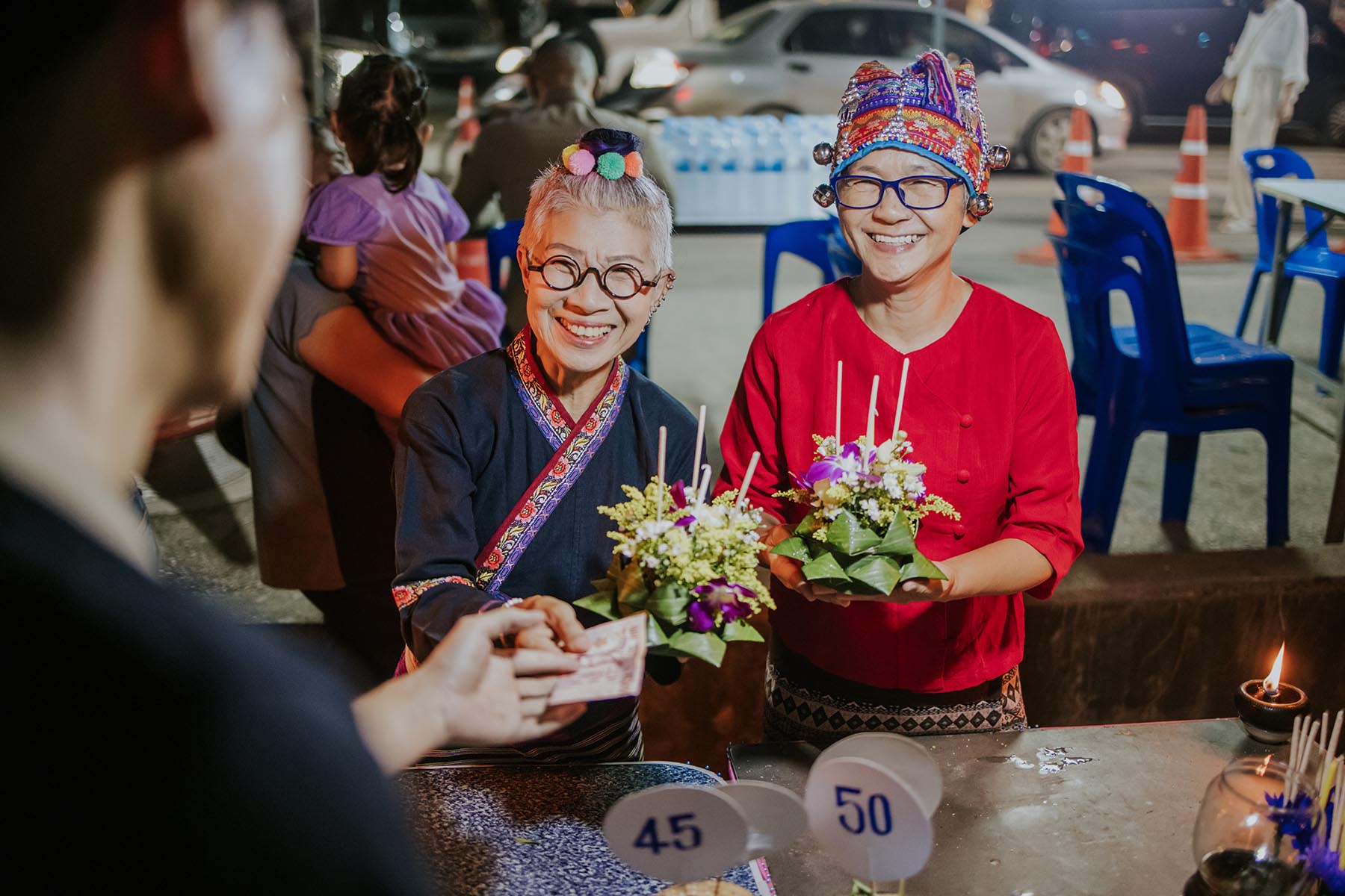 Two smiling seniors buying kratong flower floating baskets for Loy Kratong festival.