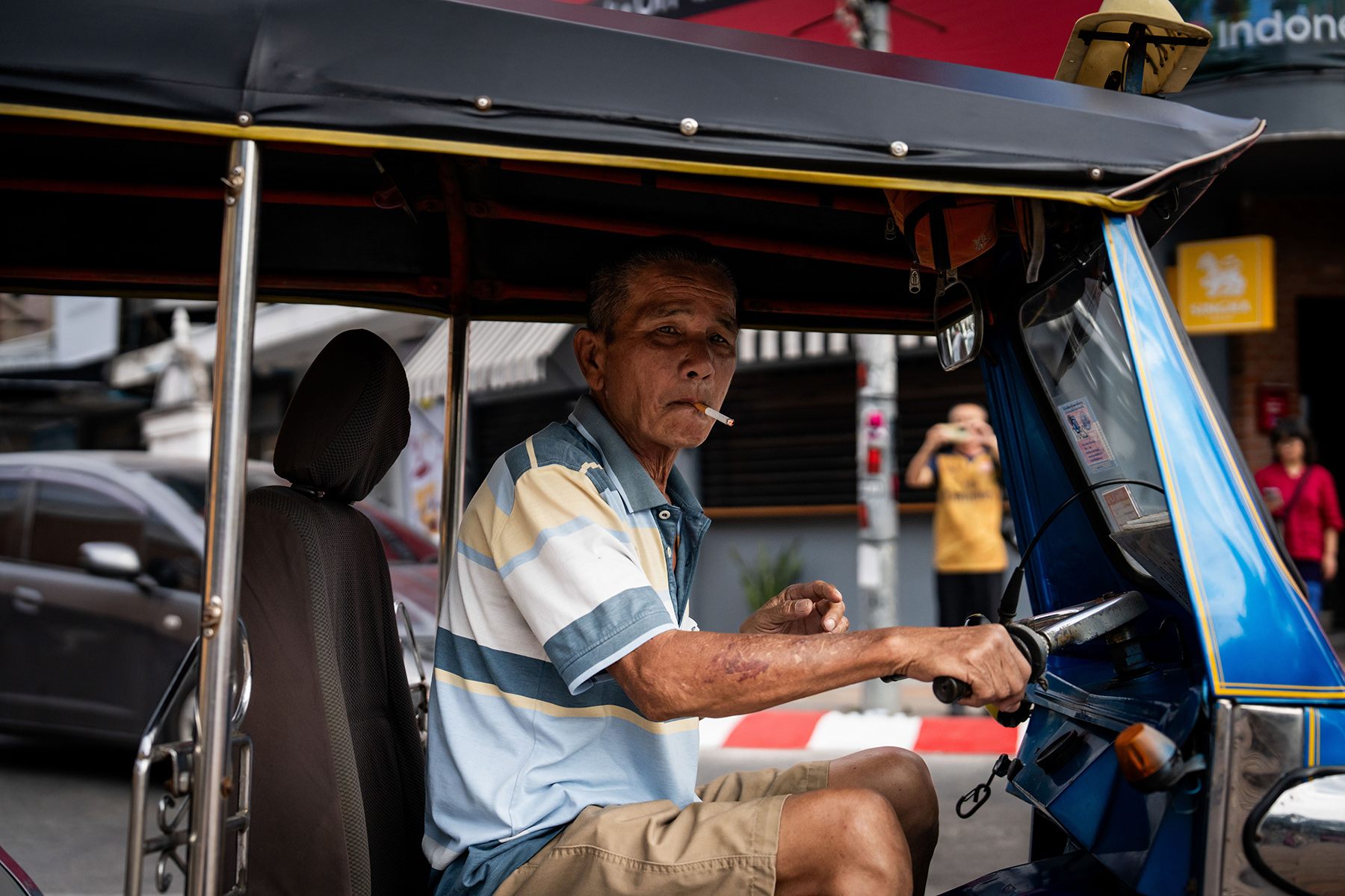 A tuk-tuk driver in Chiang Mai smokes