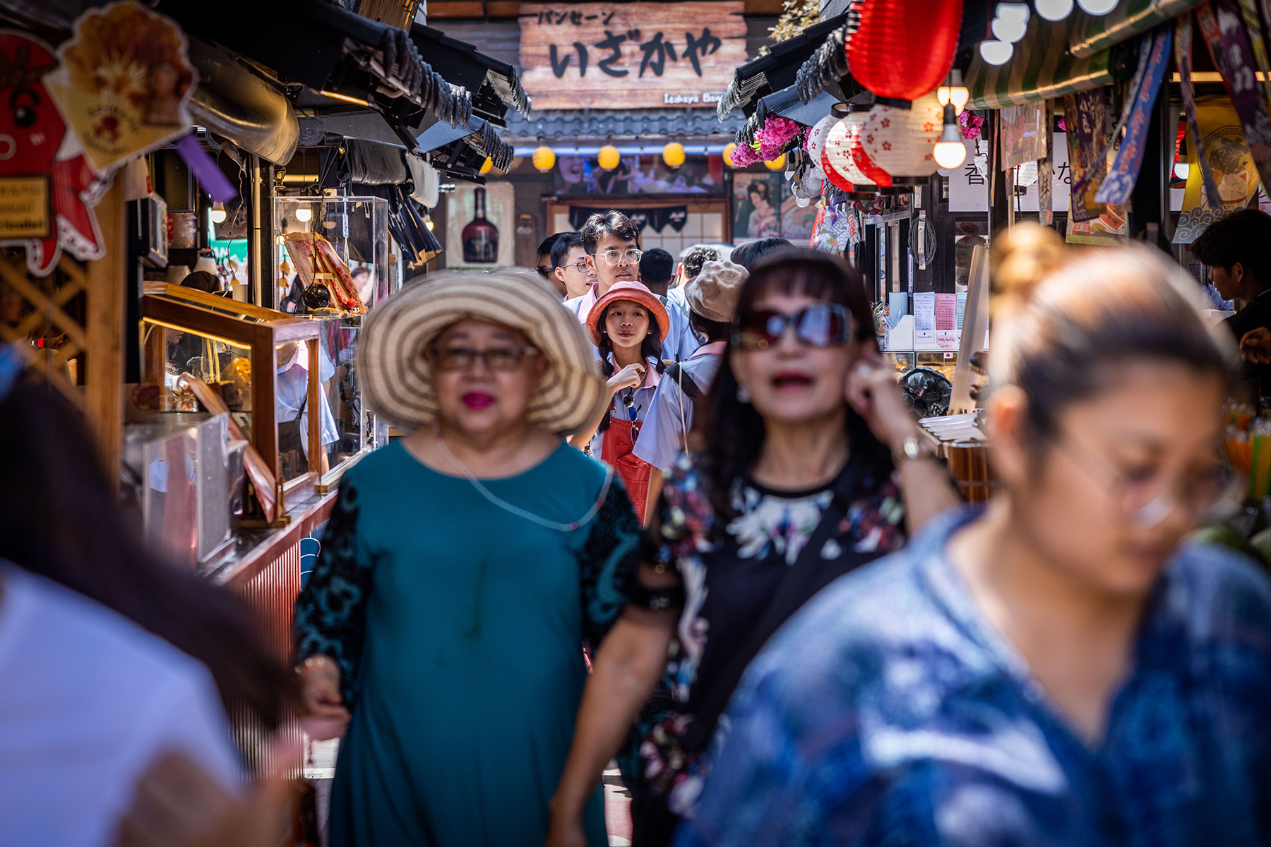Women with sunglasses walk down the Bangsaen Fish Market between a crowd