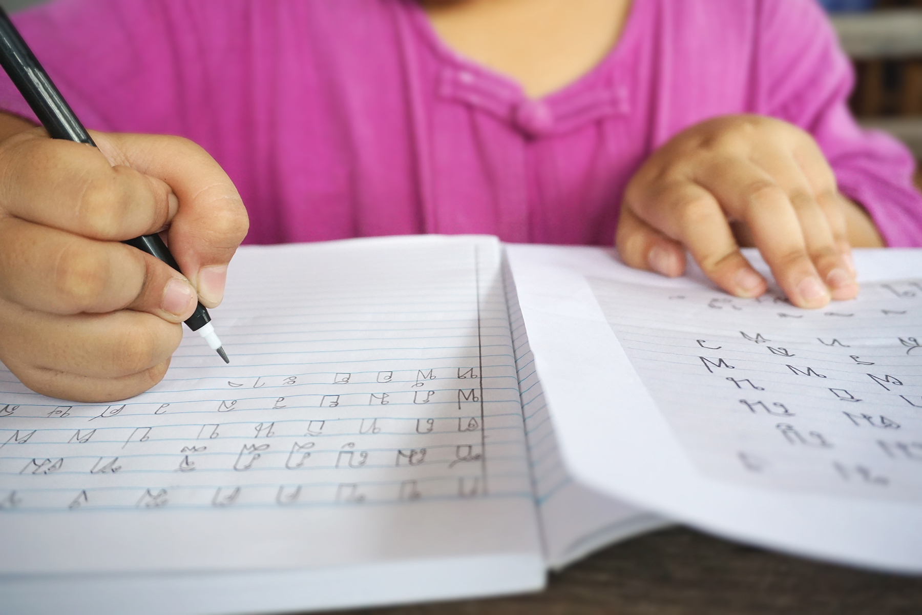 Closeup of a child writing Thai characters in a notebook