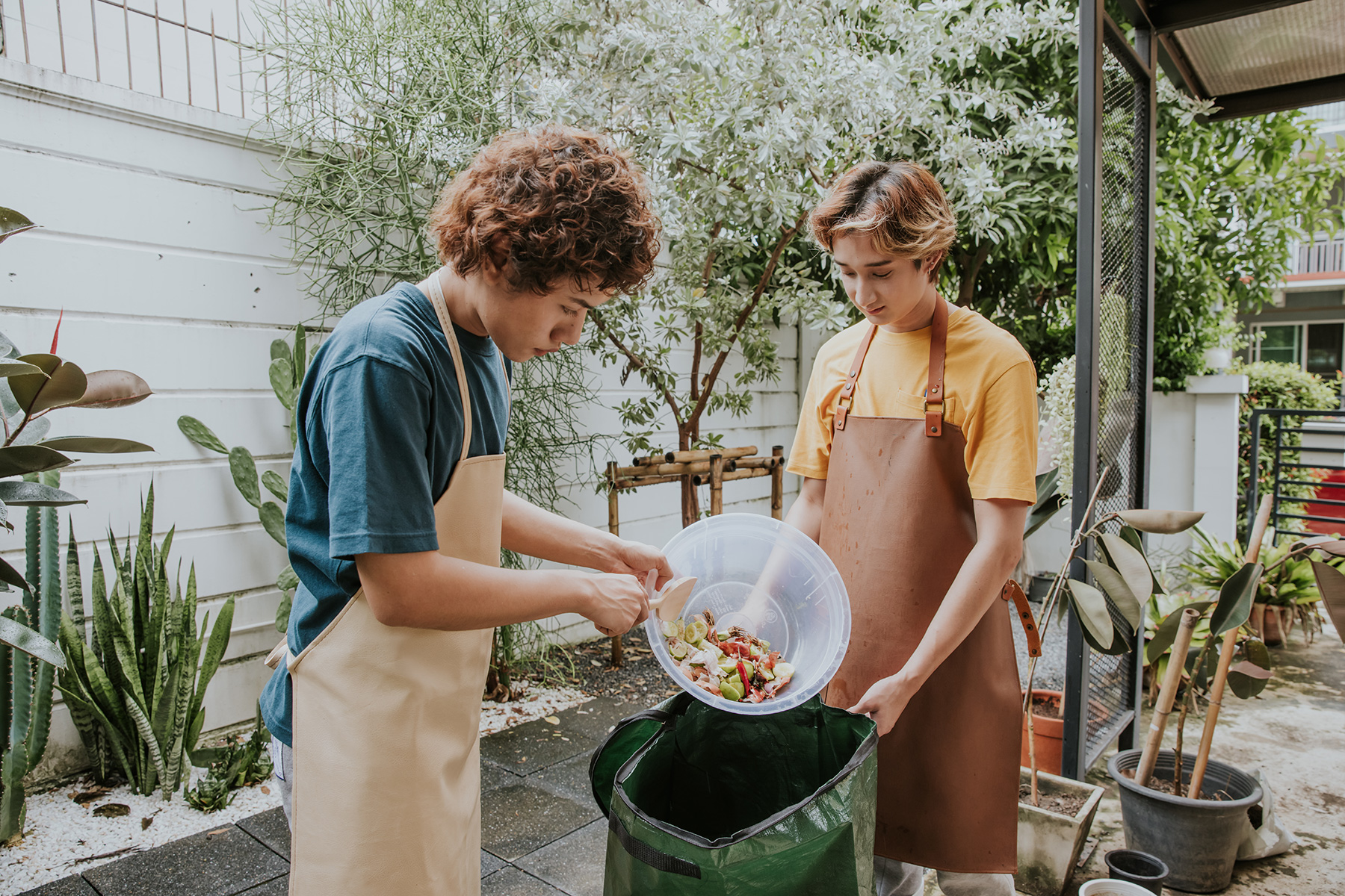 Two people composting food waste in their garden together