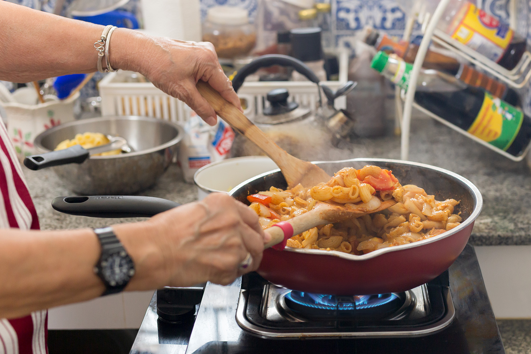 Close up of hands cooking a meal on a gas stove in Thailand

