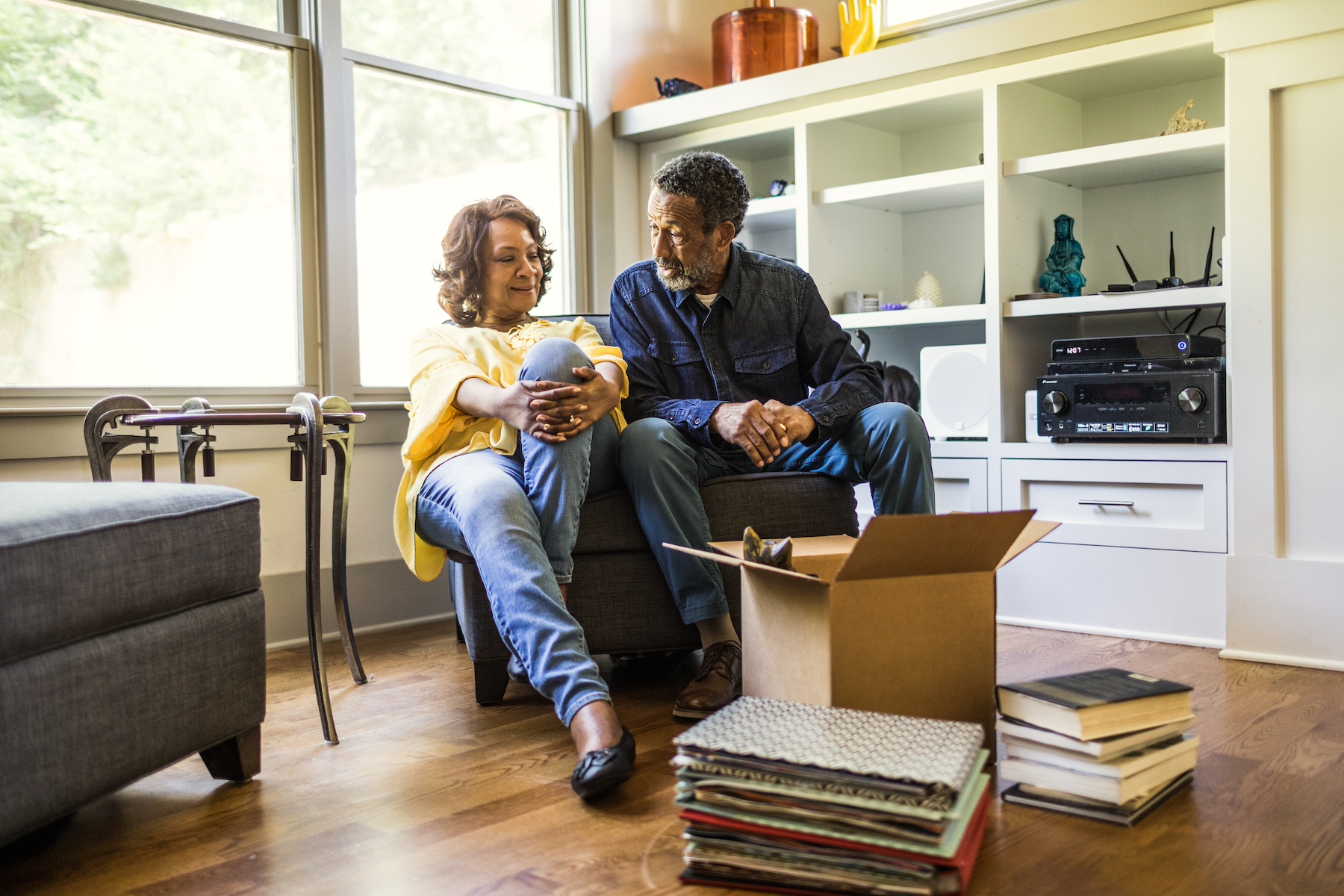 An older couple sits together to take a break from packing moving boxes at home