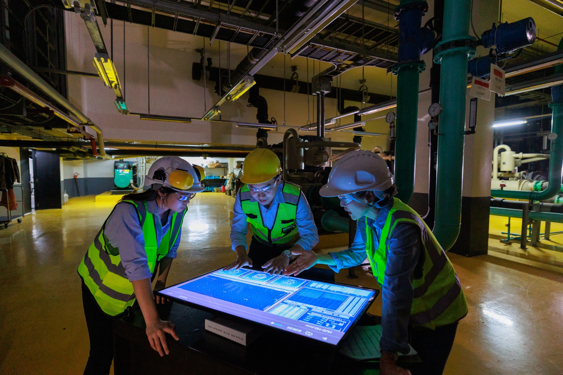 Group of engineers look at illuminated screen in machine room