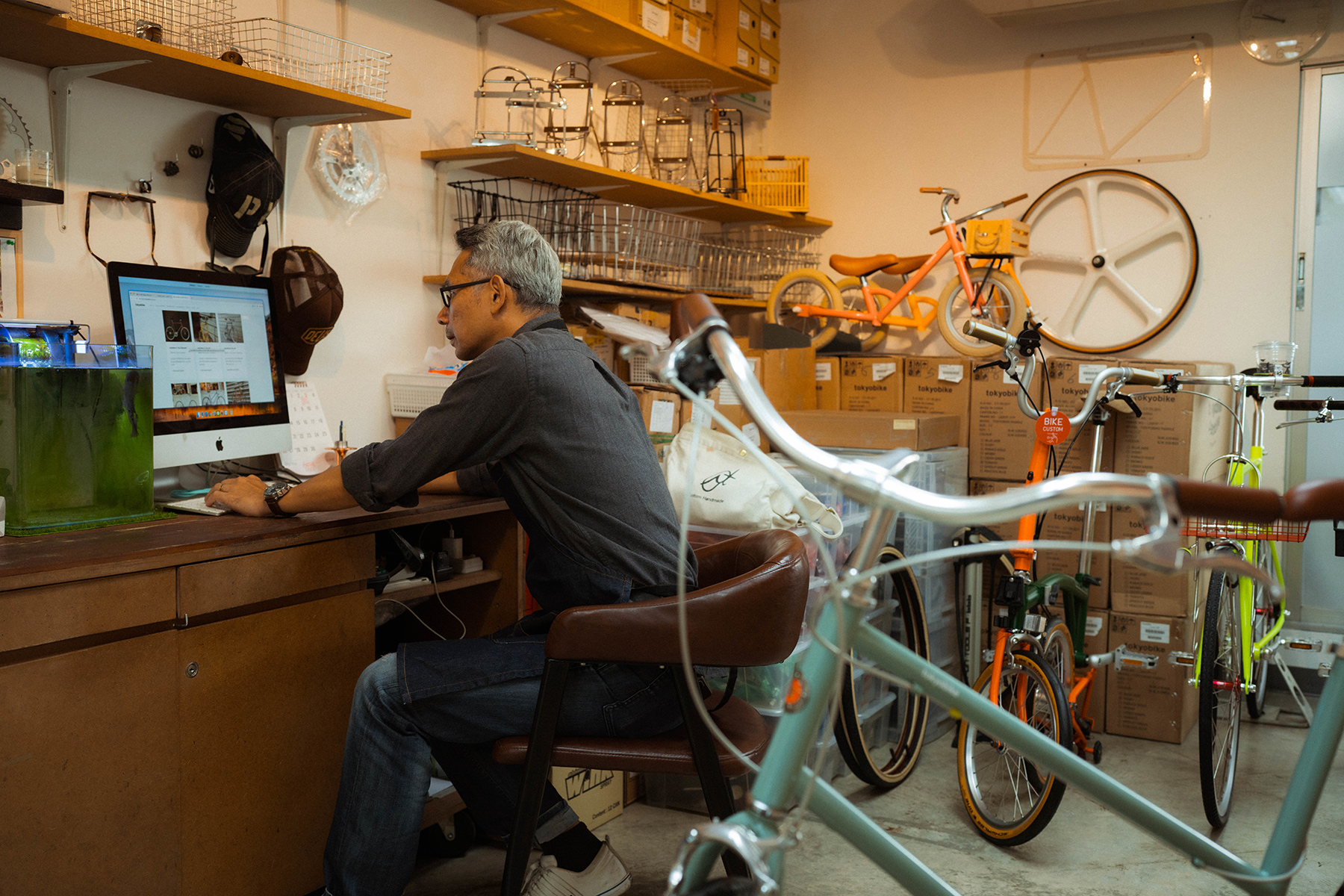 An entrepreneur in a workshop with bikes. He is working on a laptop.