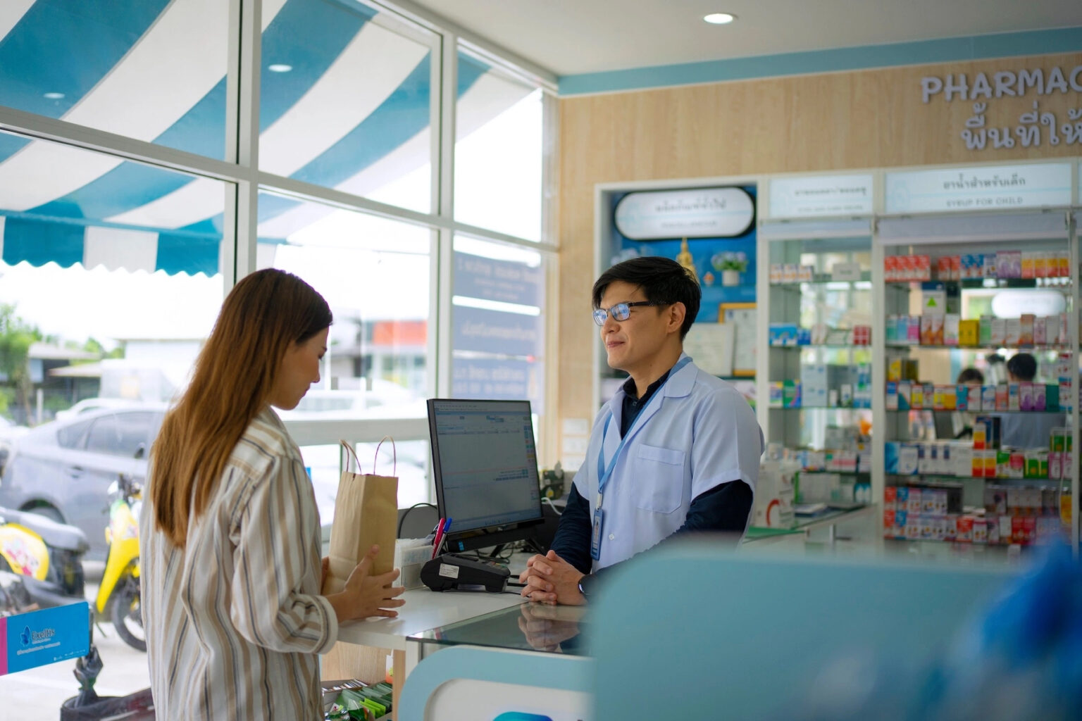 A patient stands at the counter and discusses her script or medication with the pharmacist