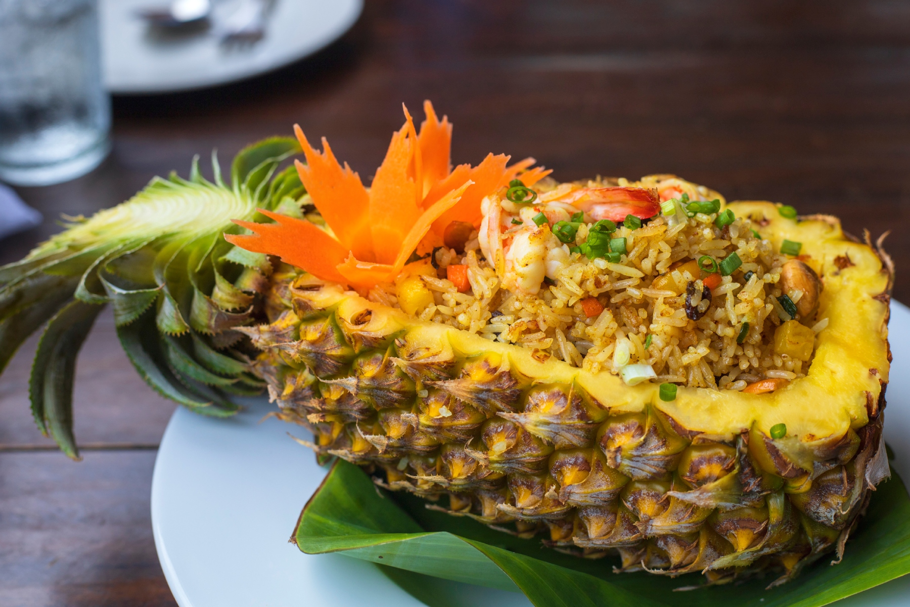 Khao pad sapparod on a plate on a table, consisting of half a hollowed out pineapple