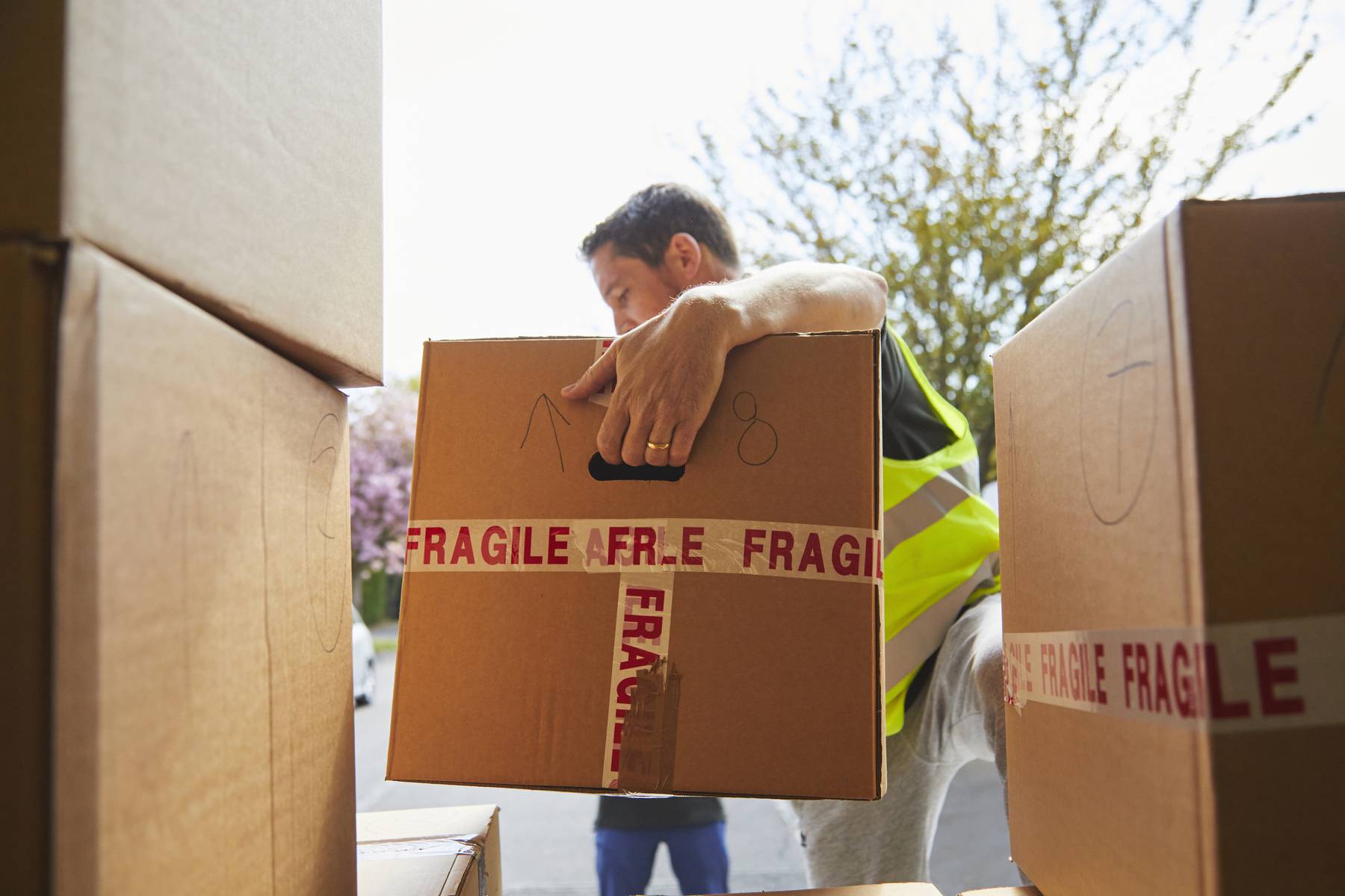 Man loads moving box marked as 'fragile' on to moving truck