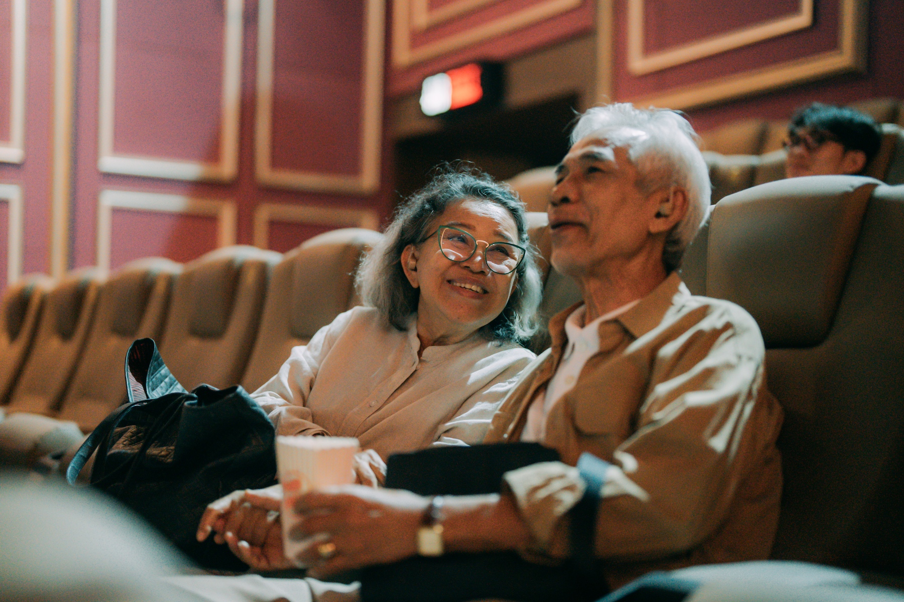 An older couple waits excitedly for the movie to start at the theater
