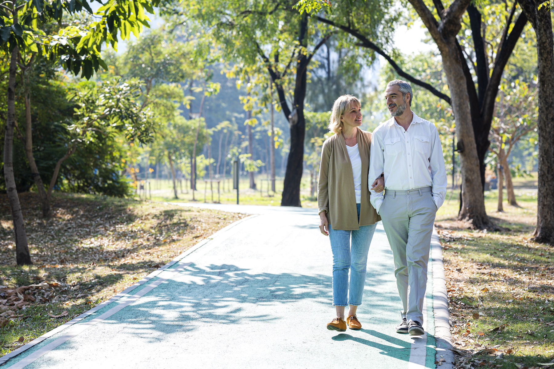 An older couple takes a morning walk together through the park