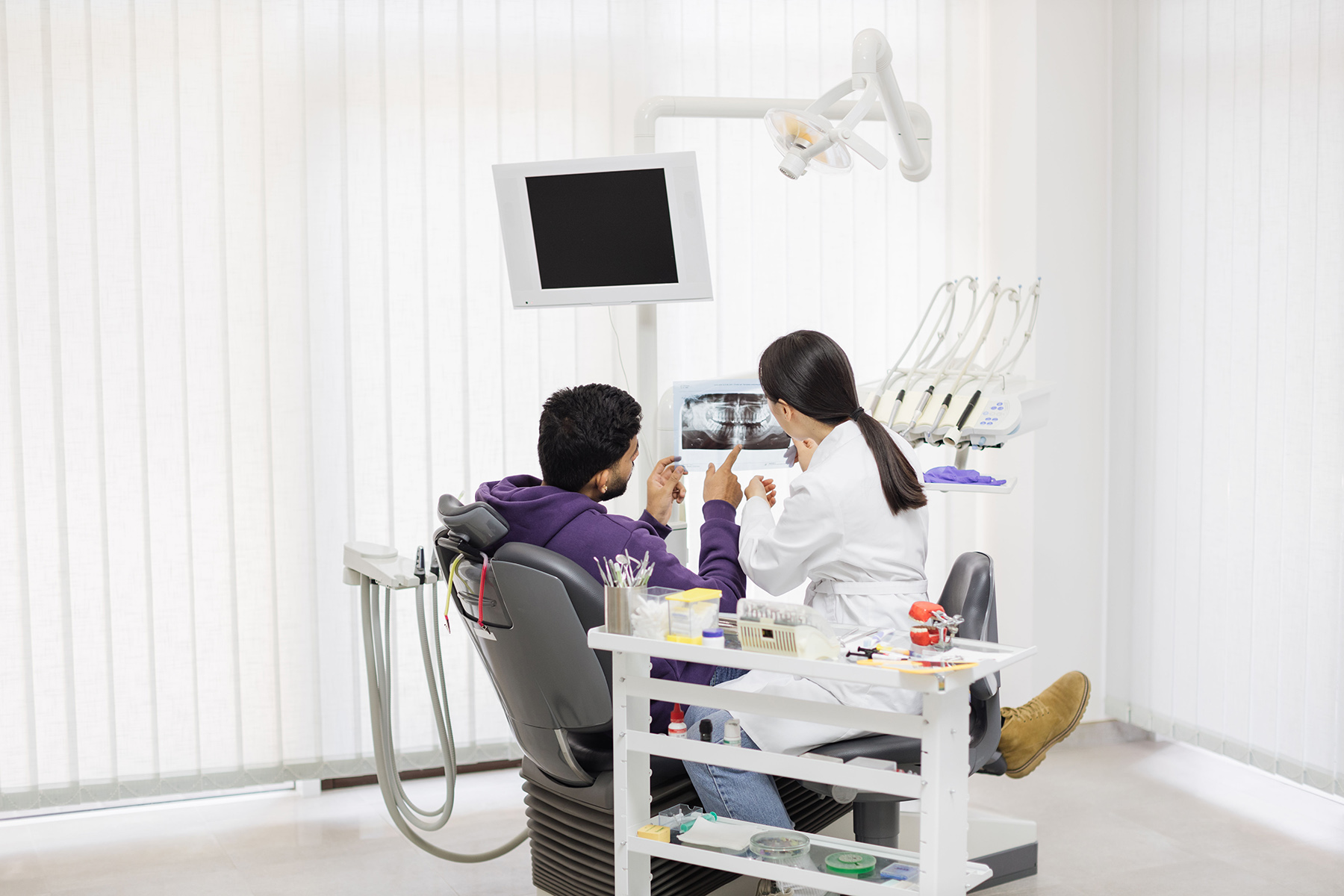 Dentist looks with patient at his dental x-rays while in the dental chair