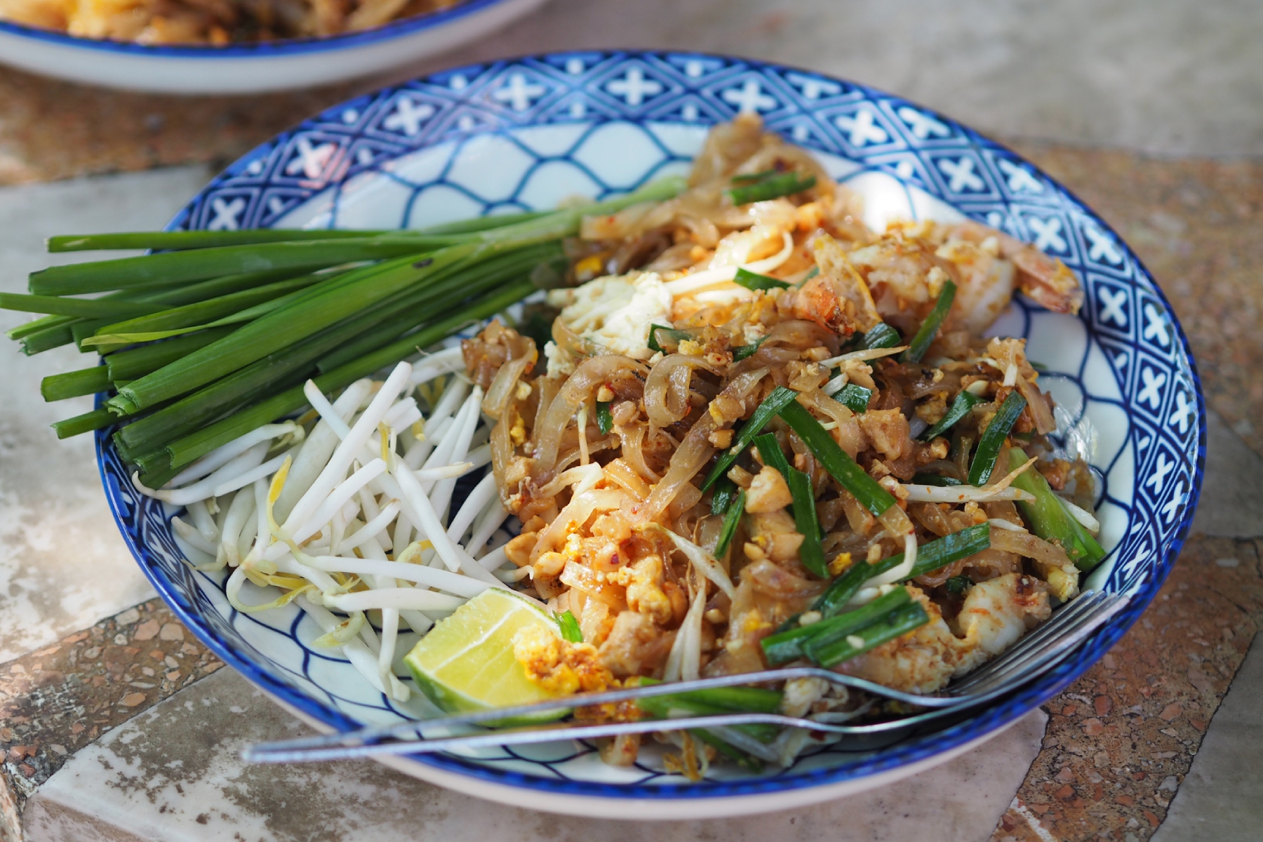 Pad thai prepared with chopped tofu in a bright blue and white plate