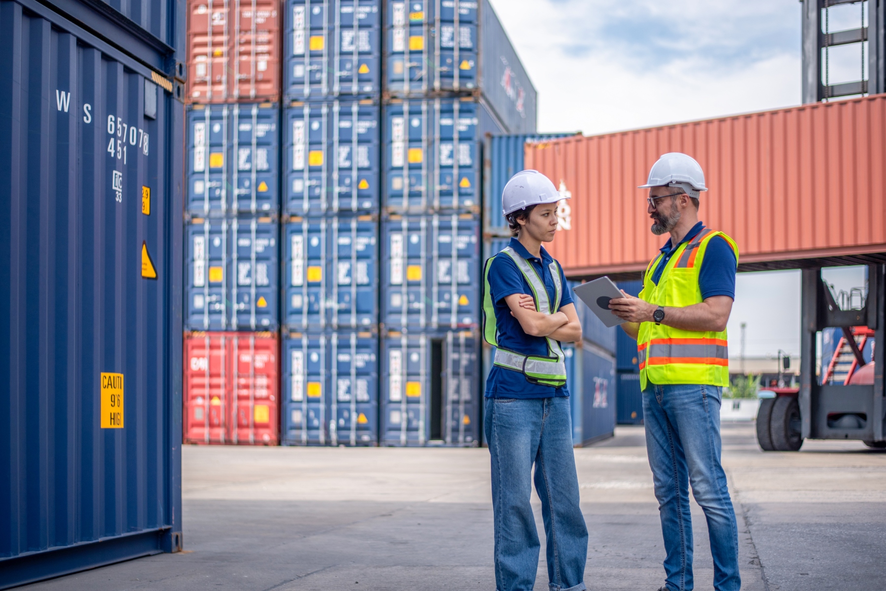 Two logistics workers having discussion next to shipping containers 