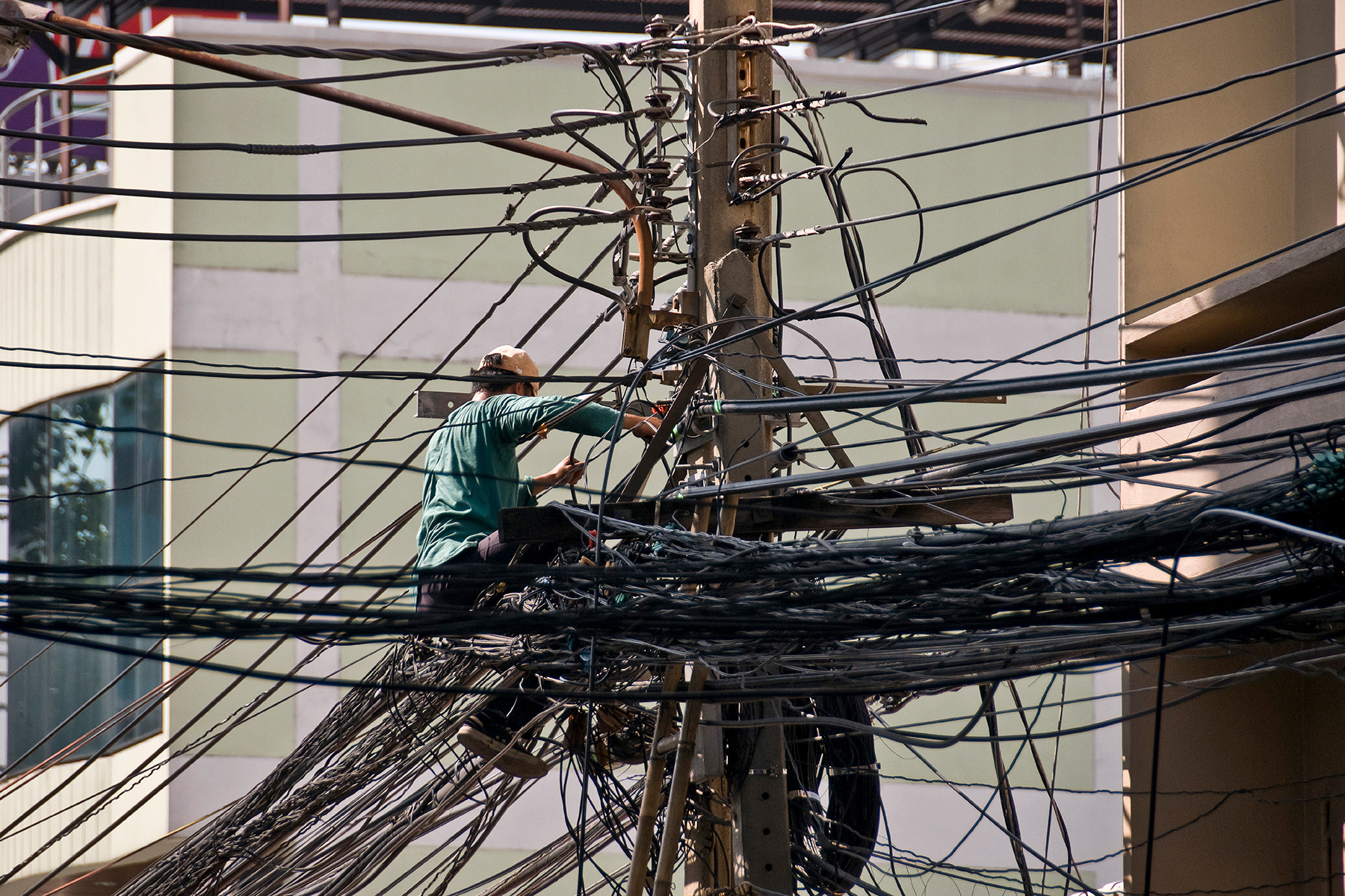 Repair worker on a telephone pole surrounded by wires.