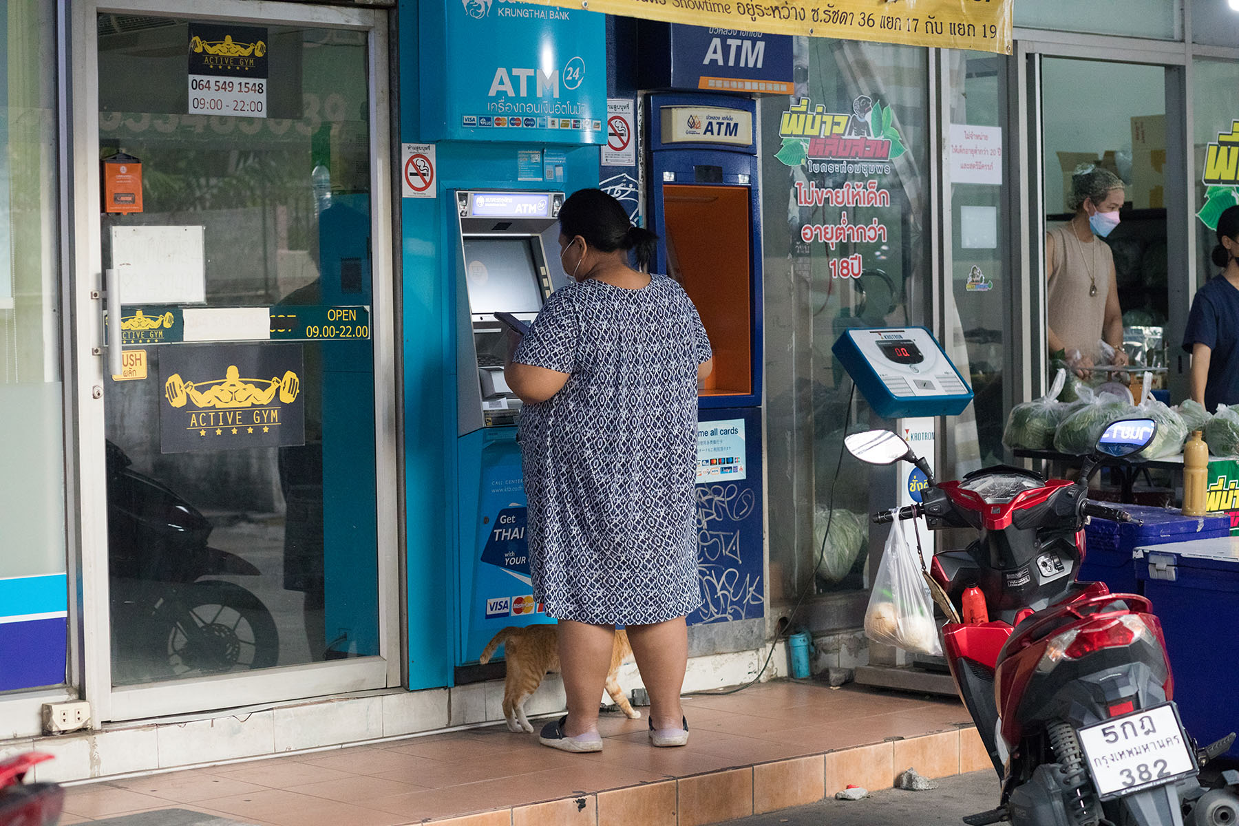Woman is taking out money from an ATM in the district of Bangkok Chatuchak.
