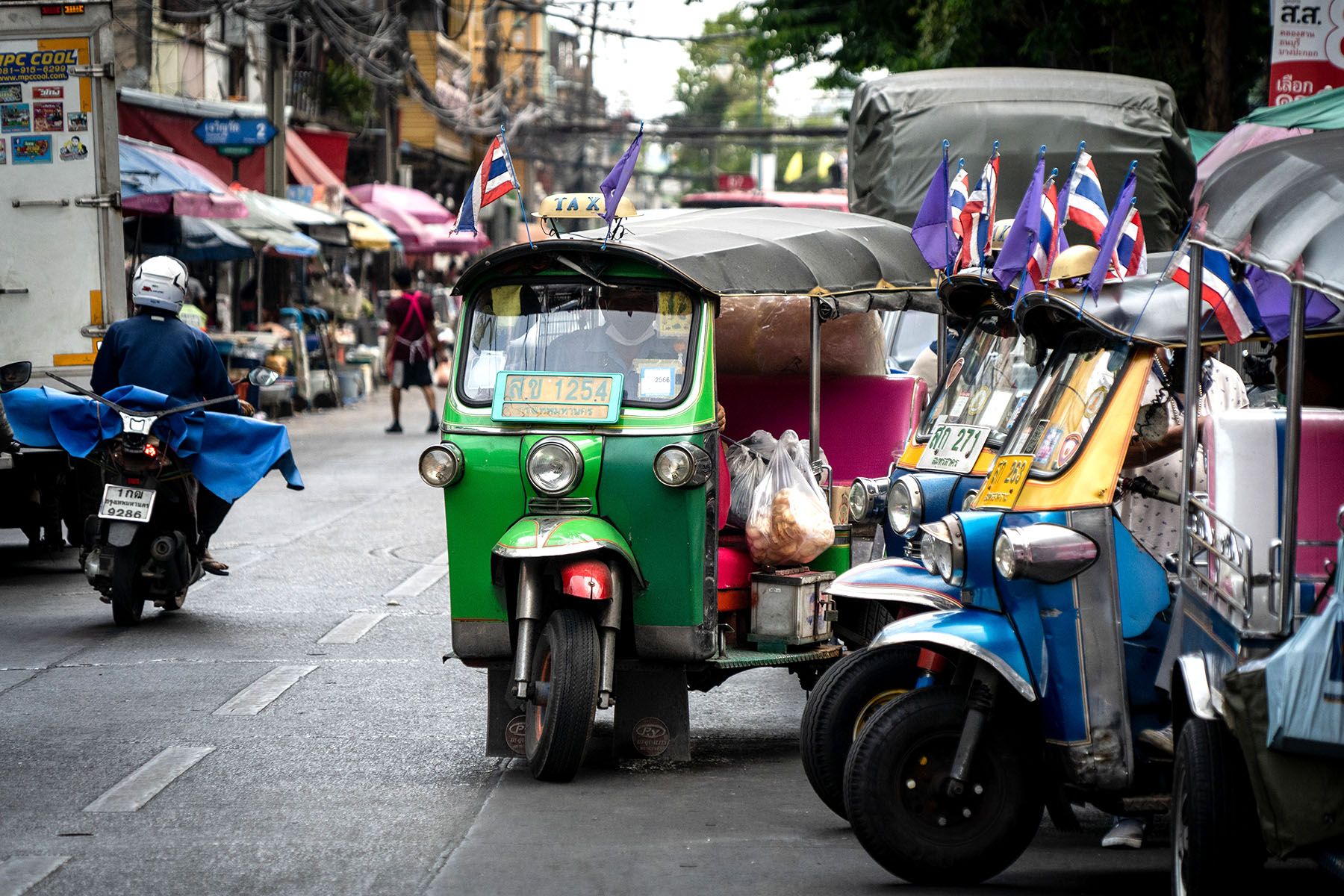 A tuk-tuk carrying loads of bread while leaving the market in Bangkok.