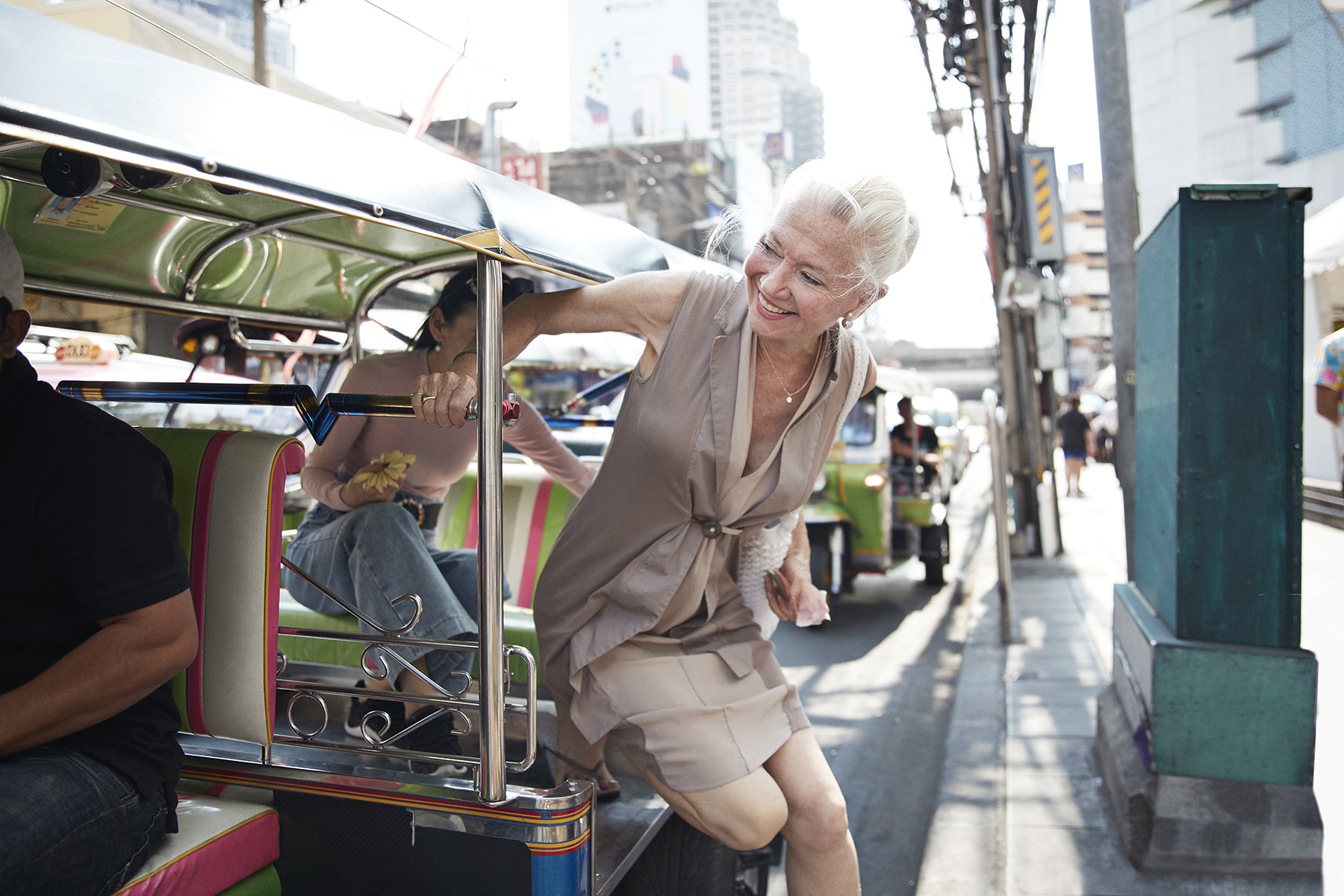 A retired expat woman gets out of a tuk tuk in Thailand

