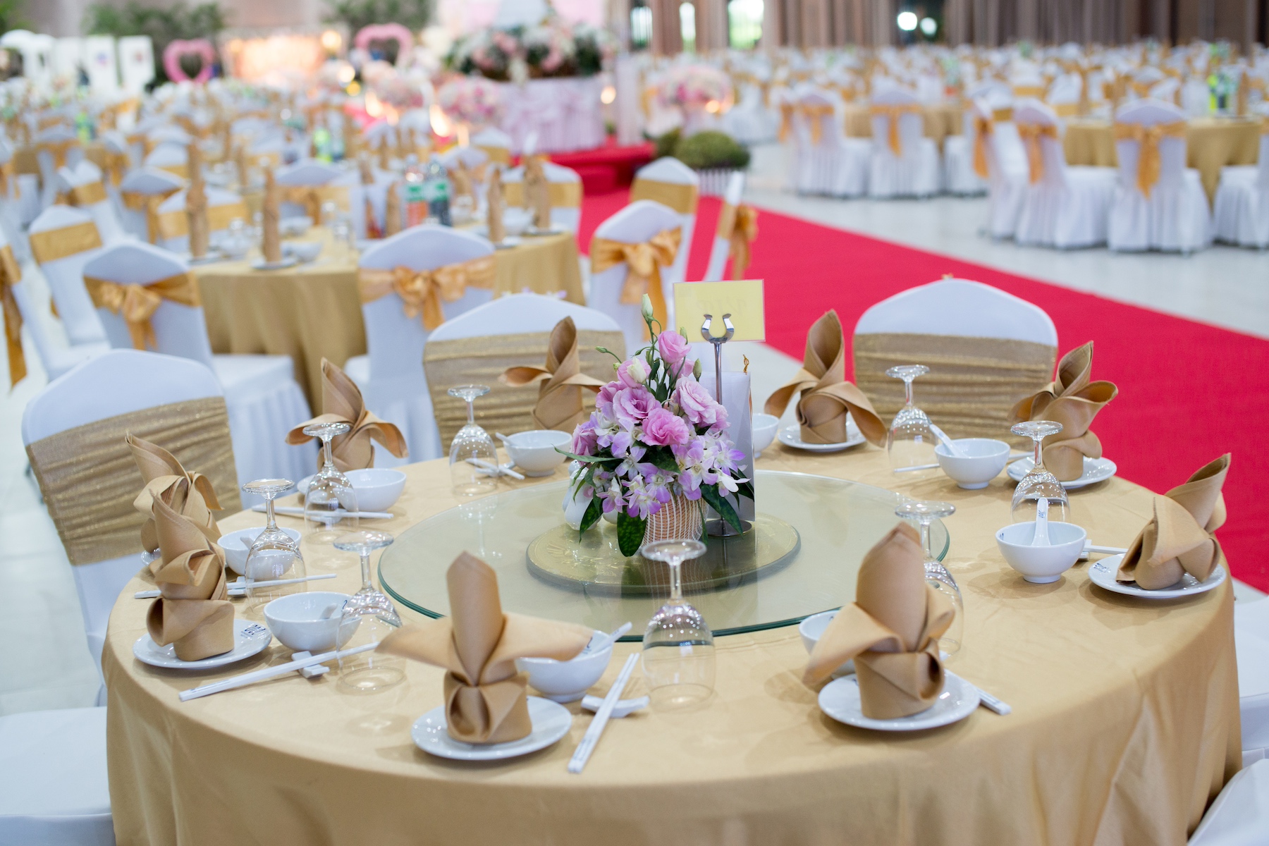 A vast banquet hall with round tables decorated for a very large wedding