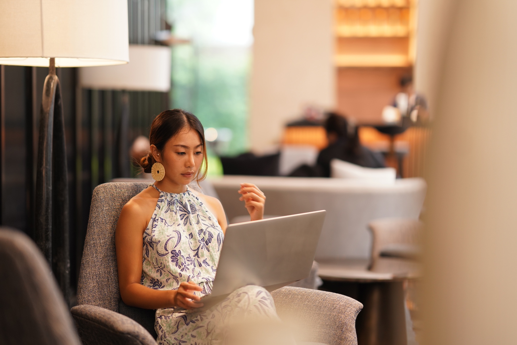 A business woman sits in a luxury hotel lobby using her laptop