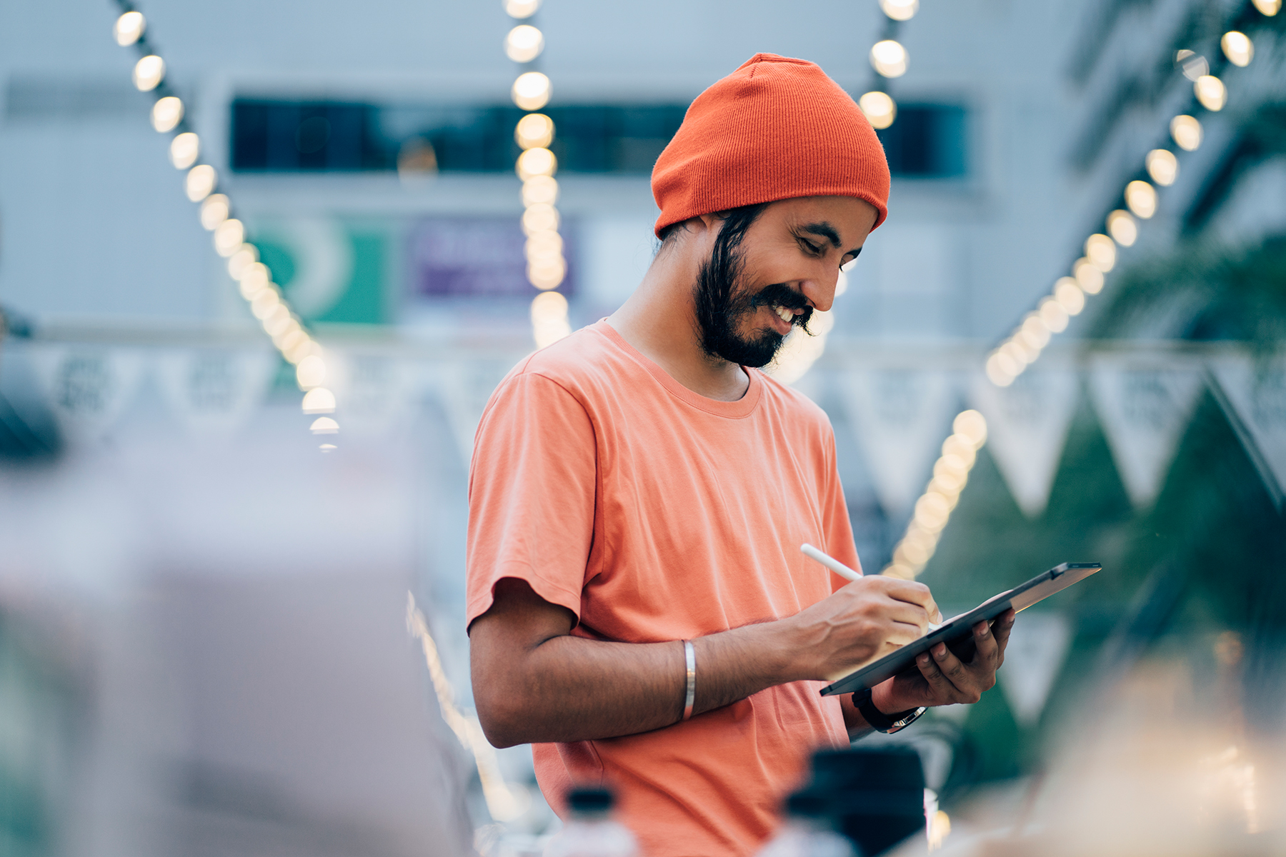 Happy man in orange hat and t-shirt working on a tablet