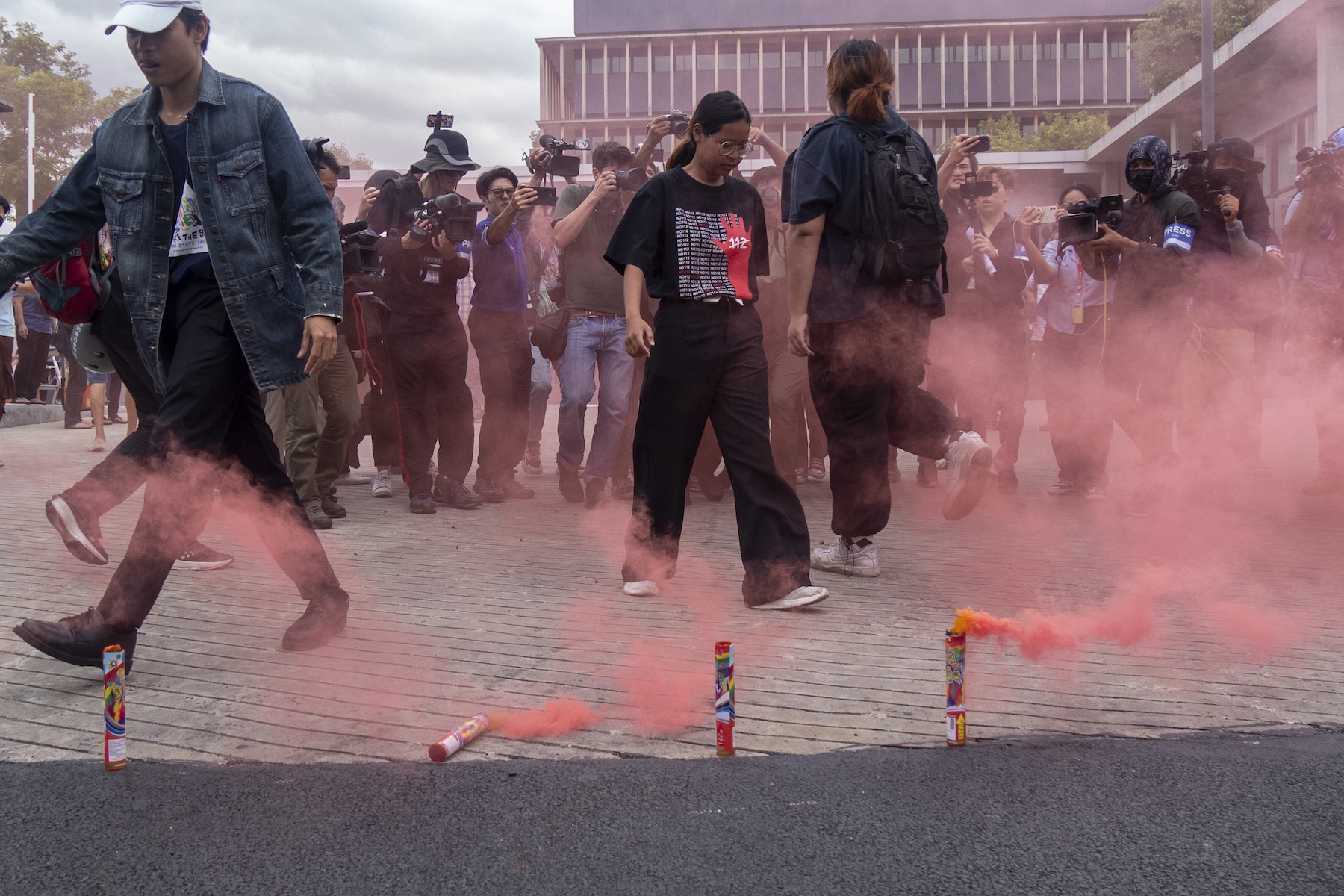 Supporters of Pita Limjaroenrat and the Move Forward Party walk in front of smoke bombs at the gates of Parliament in Bangkok, Thailand