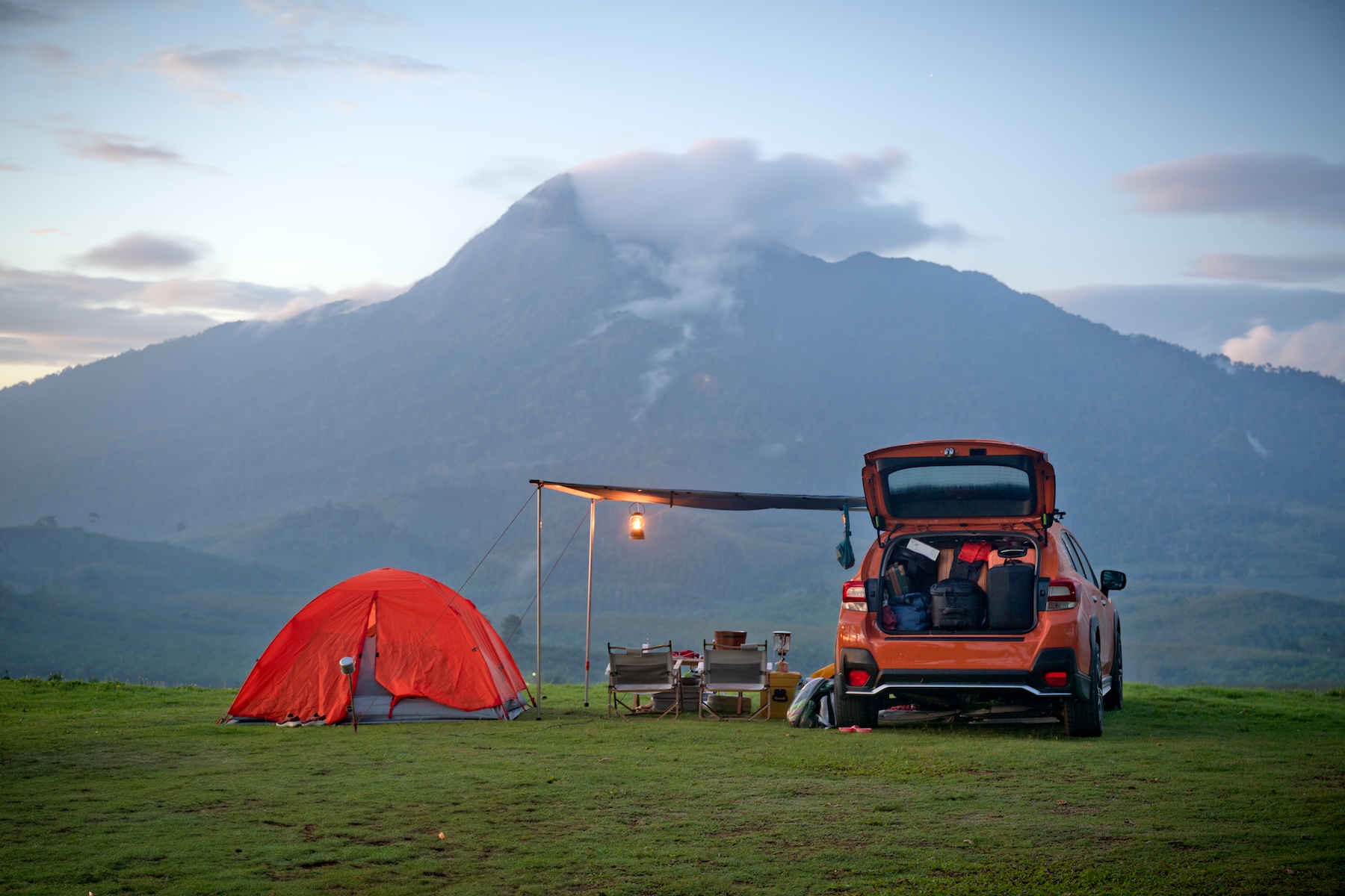 Camping scene with a car and tent featuring a mountain background
