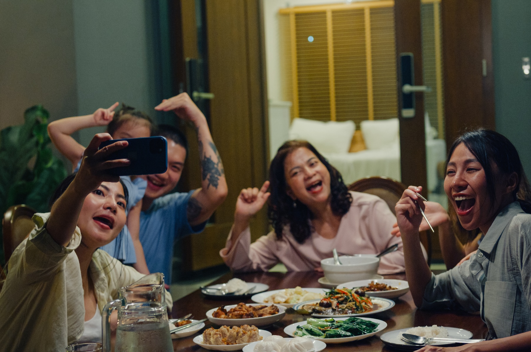 A family sits outside having dinner together and taking a selfie