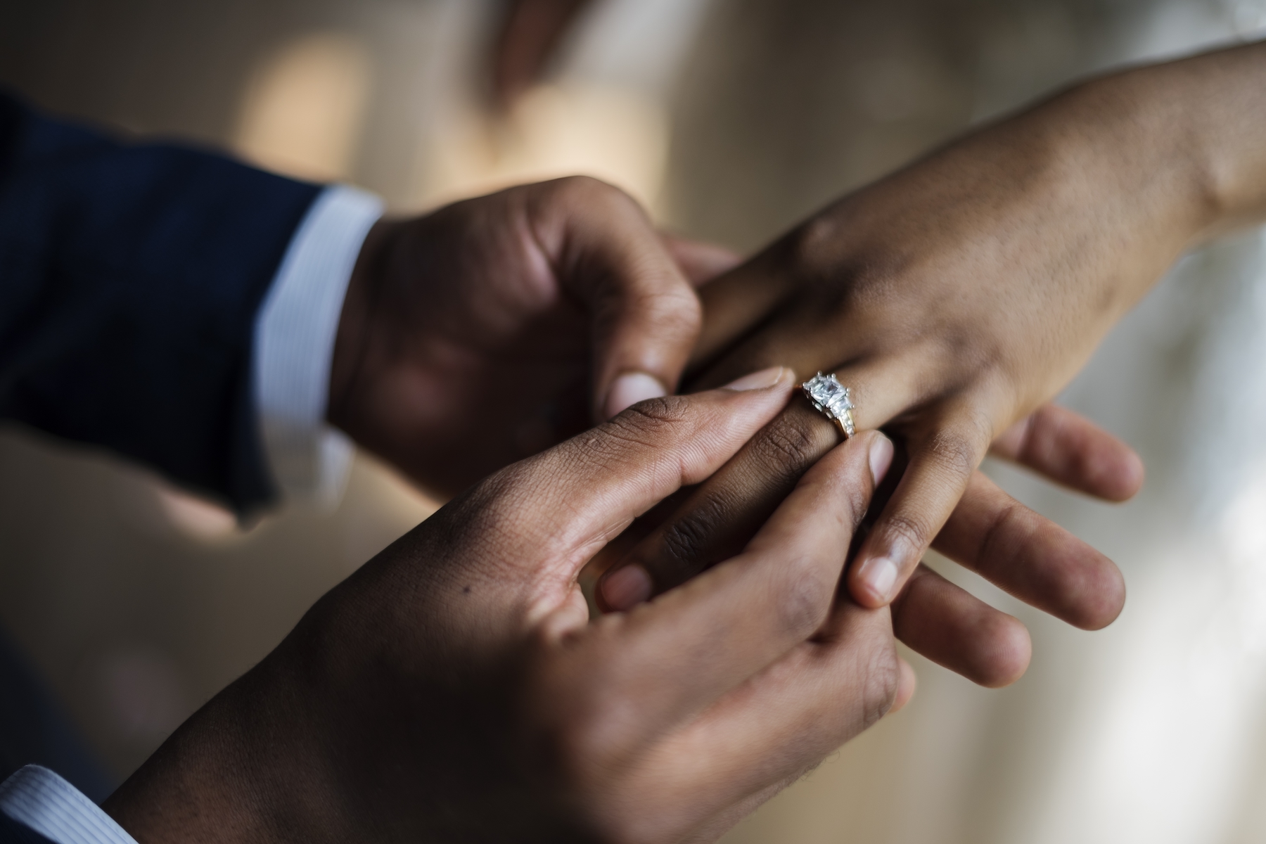 Closeup of a groom putting a wedding ring on his bride's hand during the ceremony