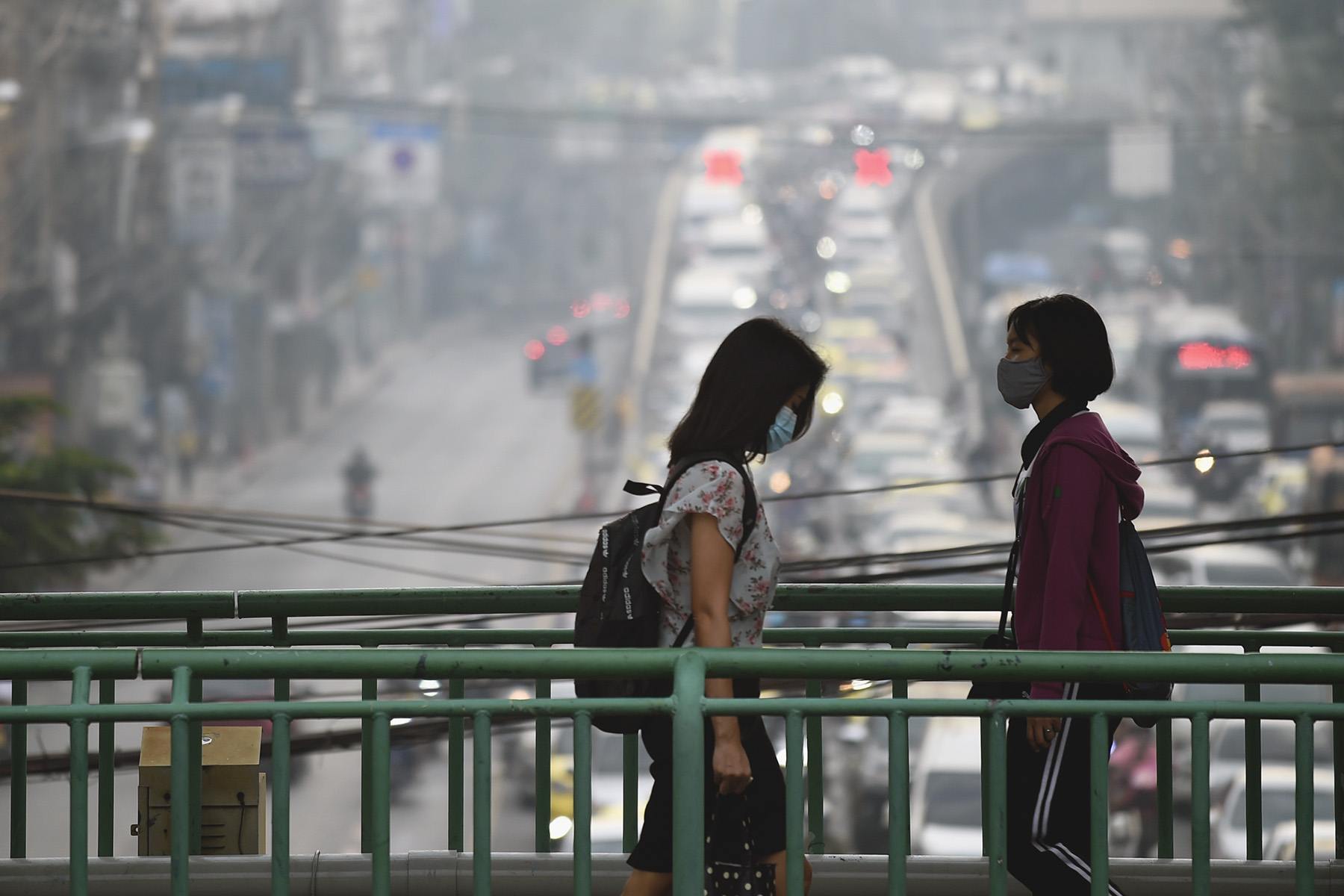 Two pedestrians wearing face masks on a smoggy day in Bangkok, Thailand.