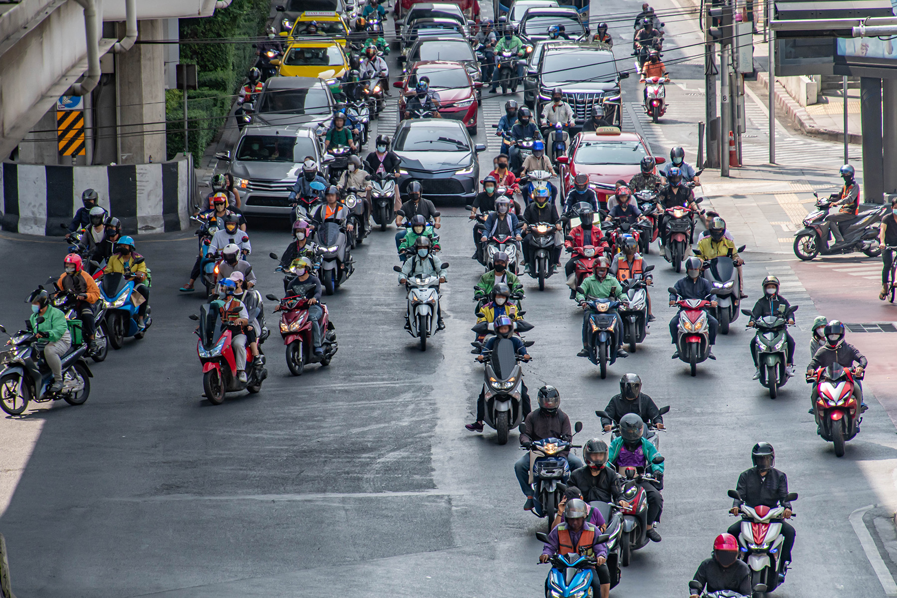 Busy road with loads of moped drivers and cars in Bangkok.