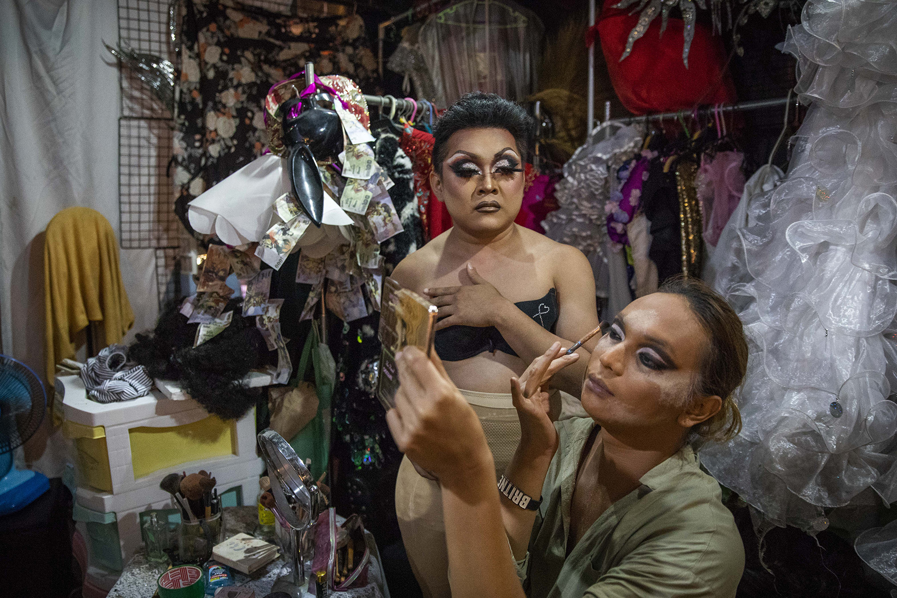 Miss Srimala helps Gisele, both drag performers, with her makeup before they go on stage.
