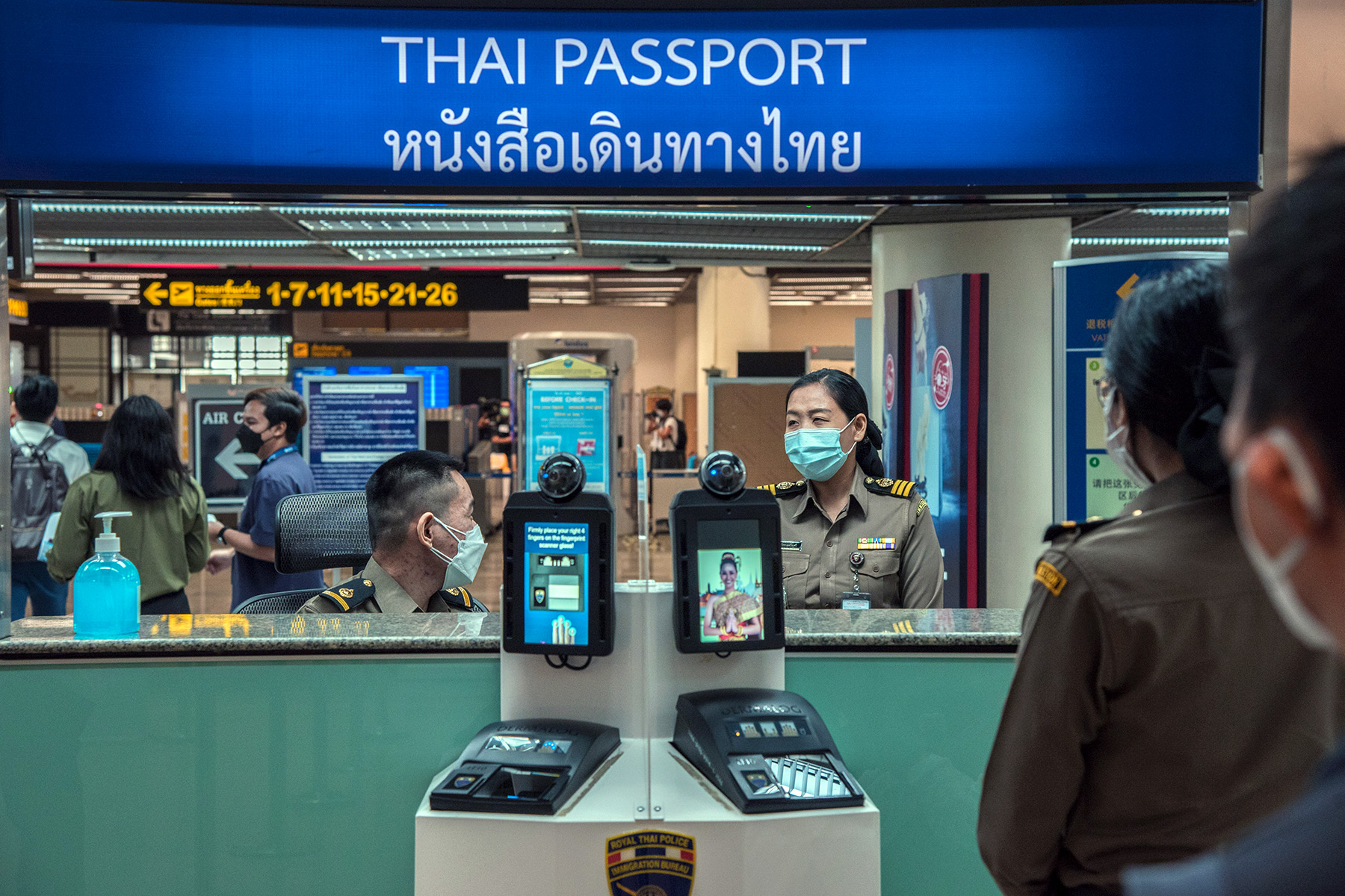 People standing in line for the passport check at Don Muang International Airport in Bangkok, Thailand. Everyone is wearing face masks.
