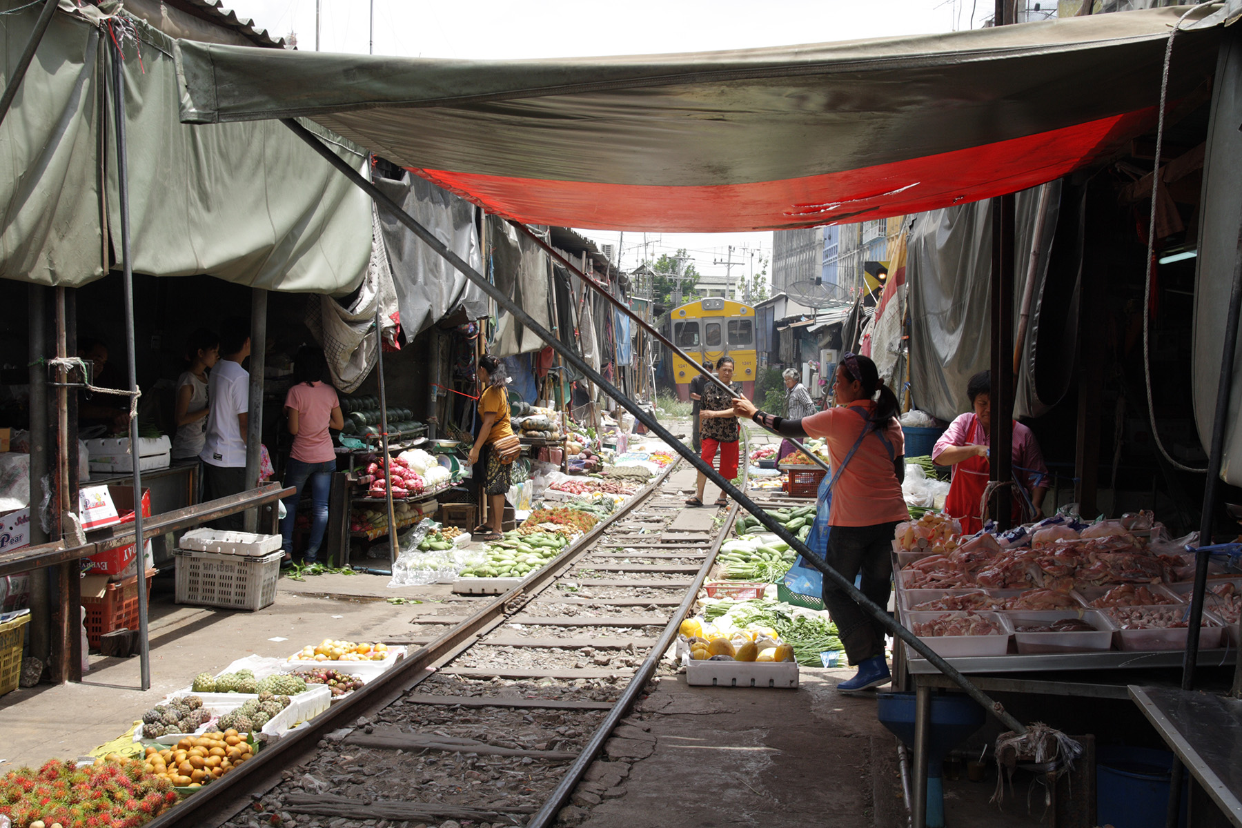 A train passing along rail tracks where vendors have built their stalls at the Maeklong Railway Market in Samut Songkram, Thailand.