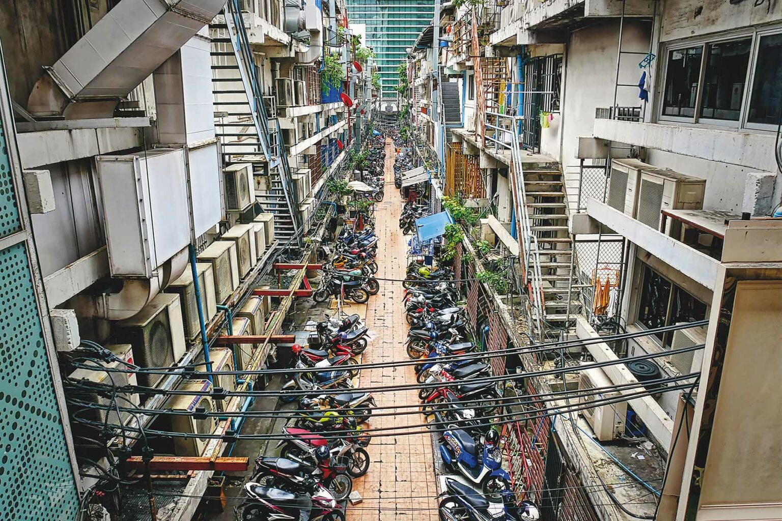 High angle view of residential flats and a back alley in an unknown city in Thailand with loads of scooters and motorcycles.