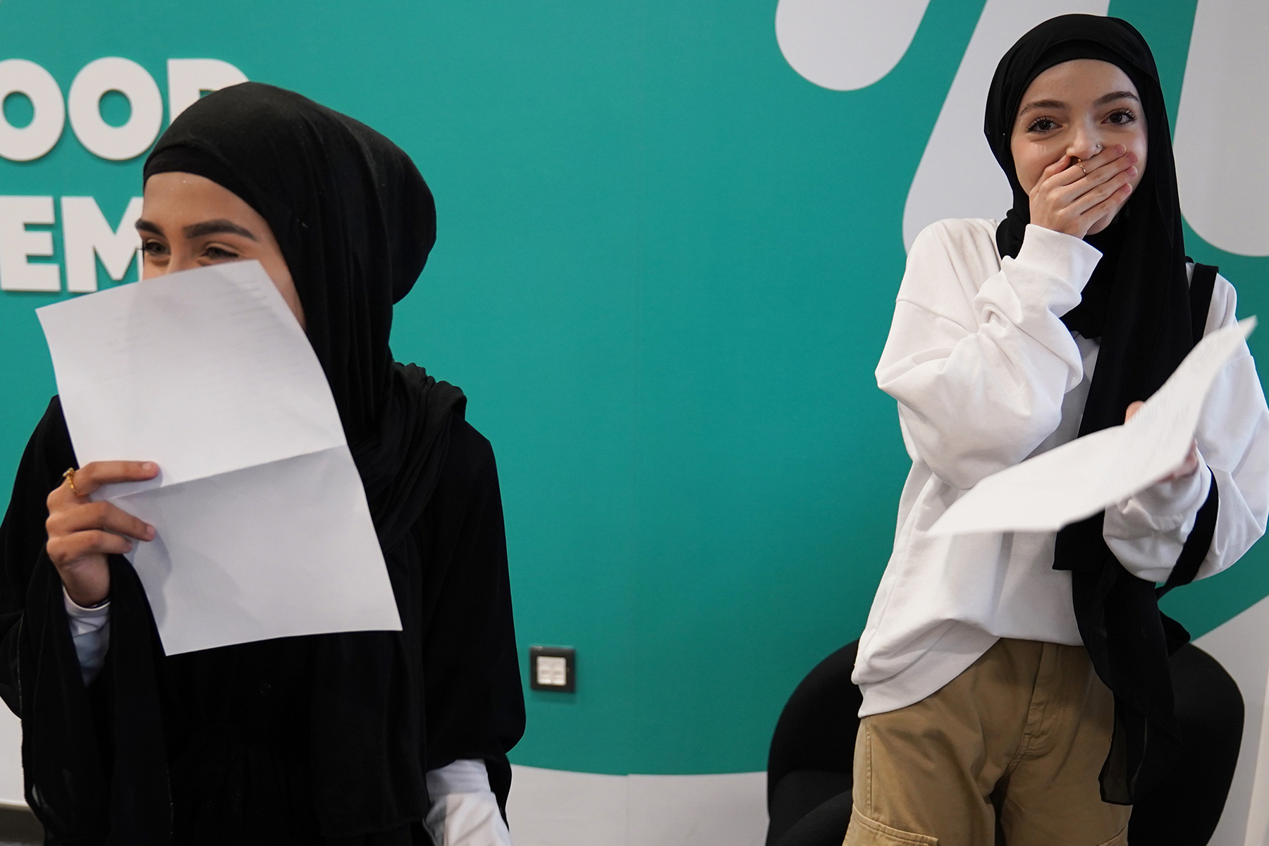 Two students with happy, surprise expressions holding exam results