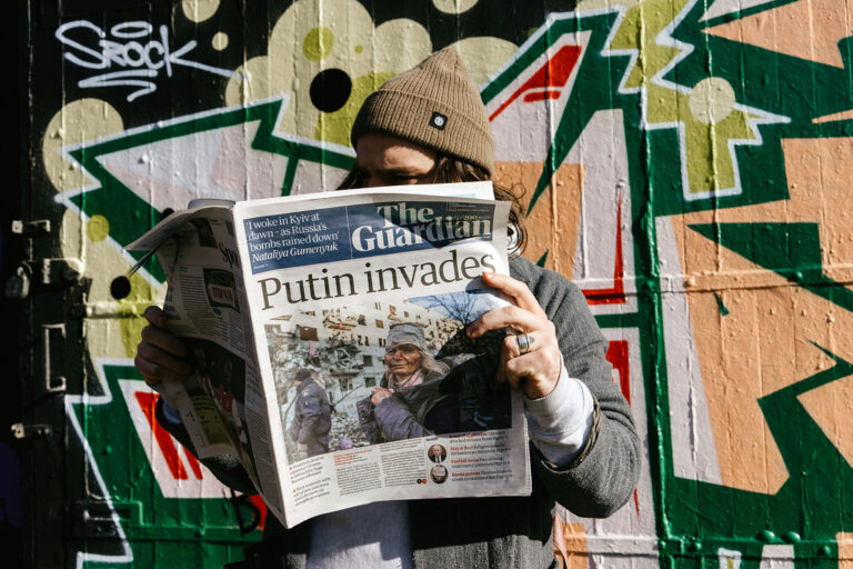 Man reading The Guardian, with a headline "Putin invades".