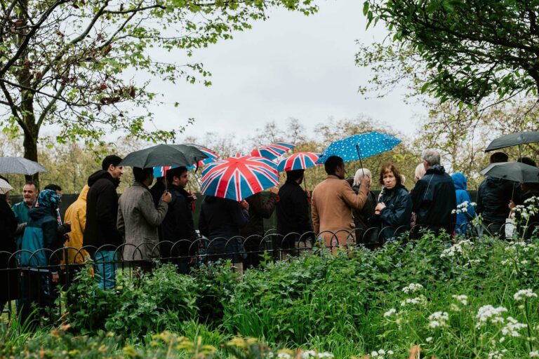 people with umbrellas standing around in the rain, UK-style