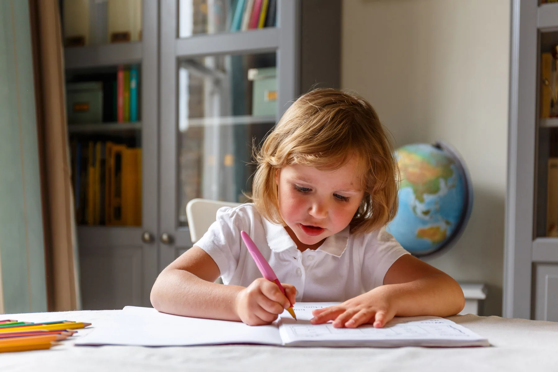 A young girl being assessed on her writing in Reception at a primary school in the UK
