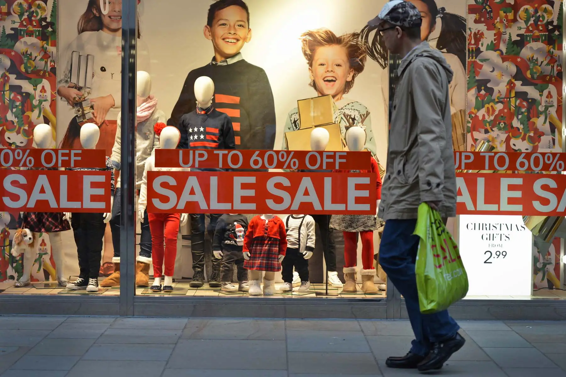 man walking past sale signs in shop windows in the UK