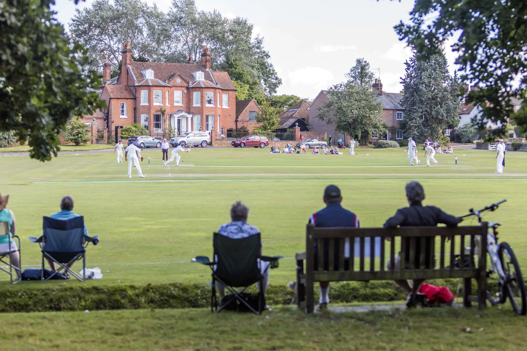 small crowd watching cricket match in English village