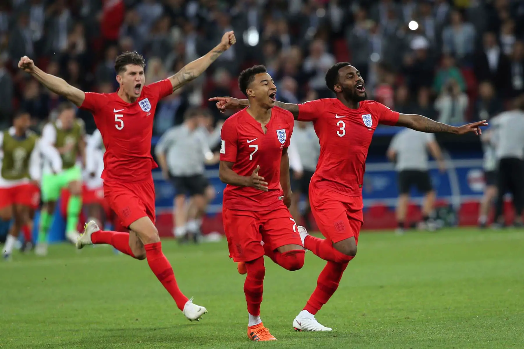 three England footballers celebrating on the pitch