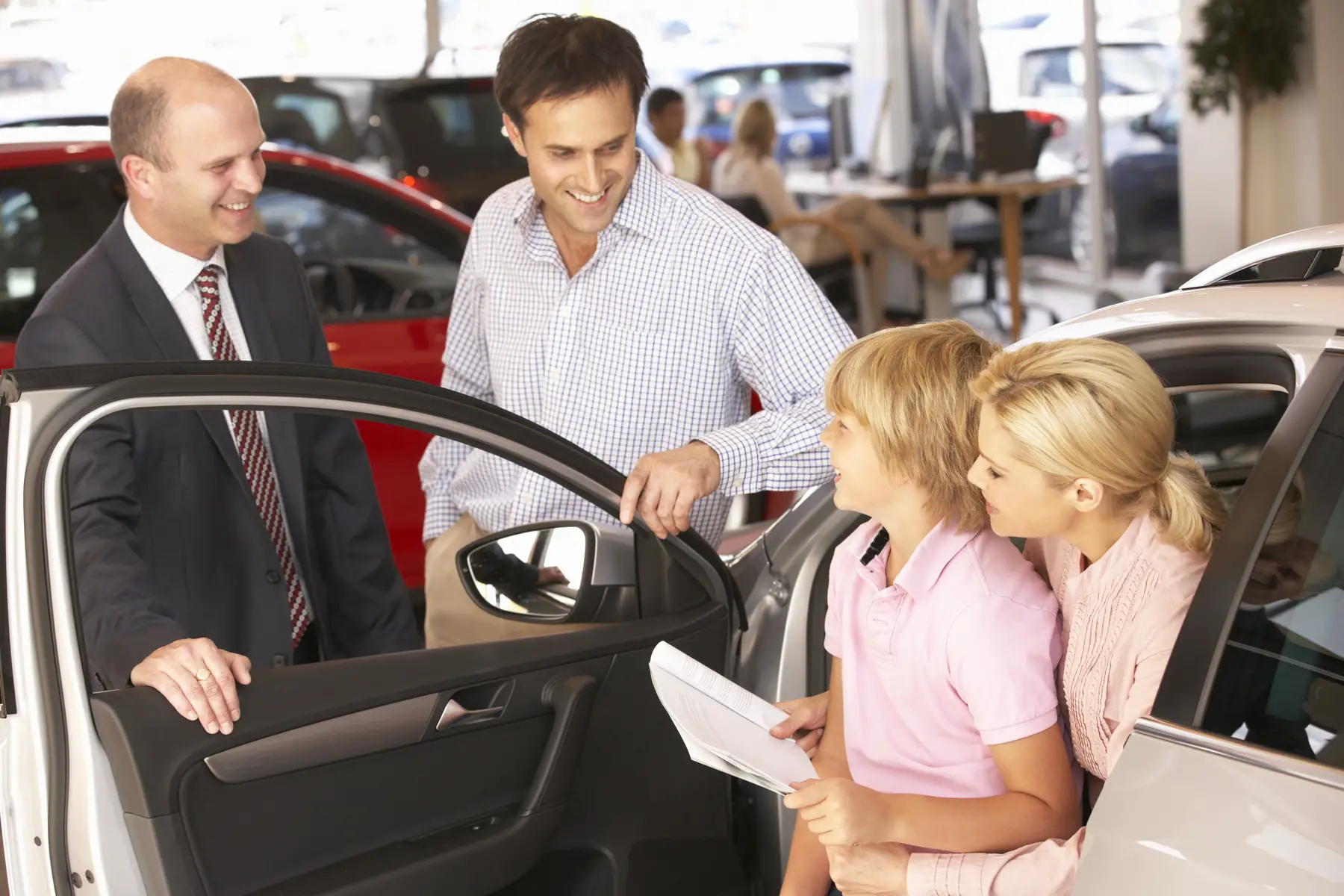 family trying out a car at a dealership with a salesman 