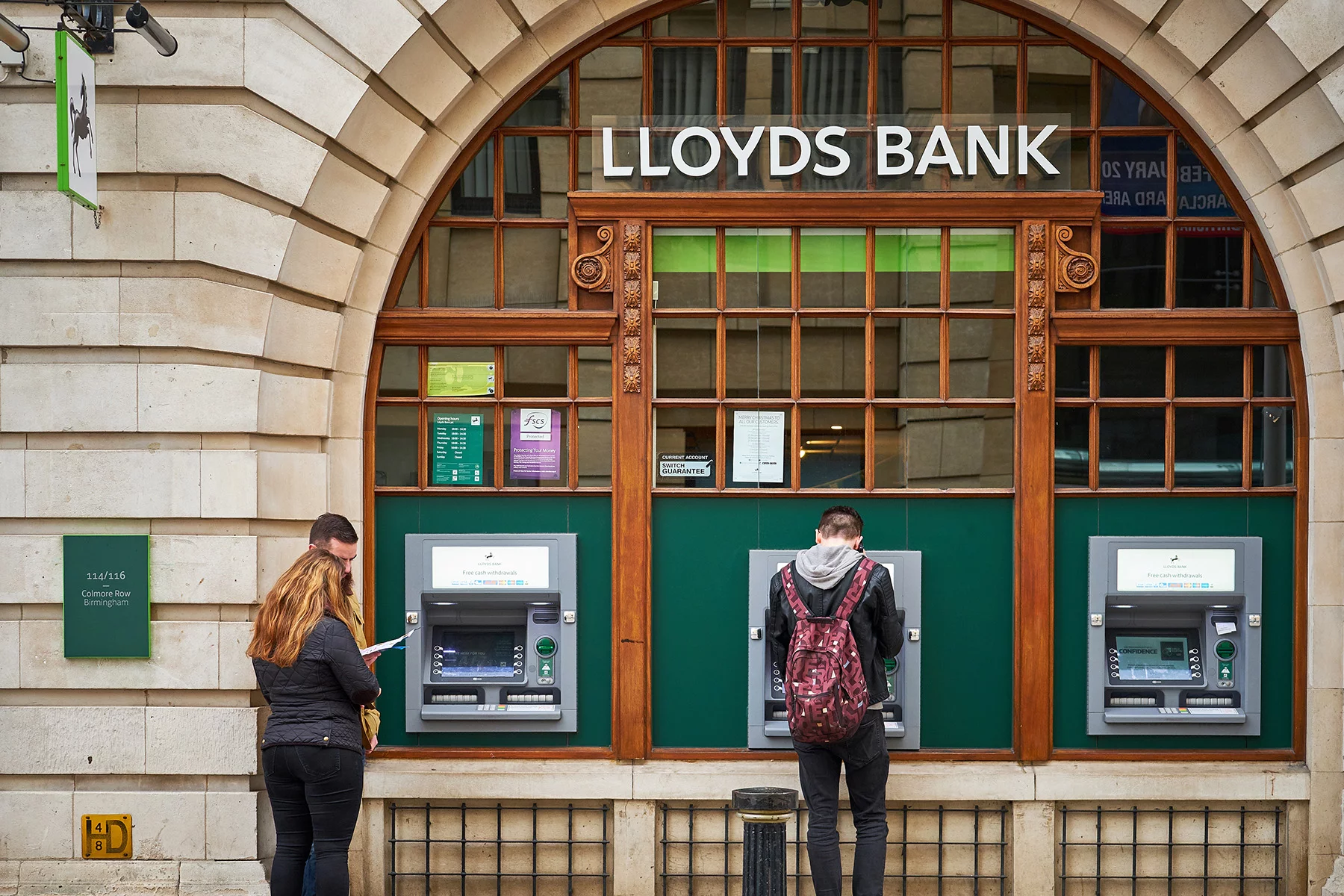 Customers using ATMs at a Lloyds Bank