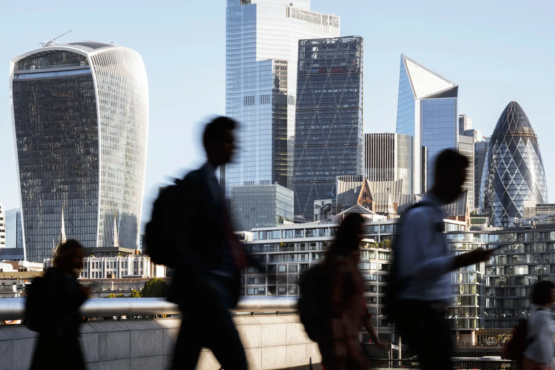 a motion shot of commuters walking past a backdrop of London's financial center