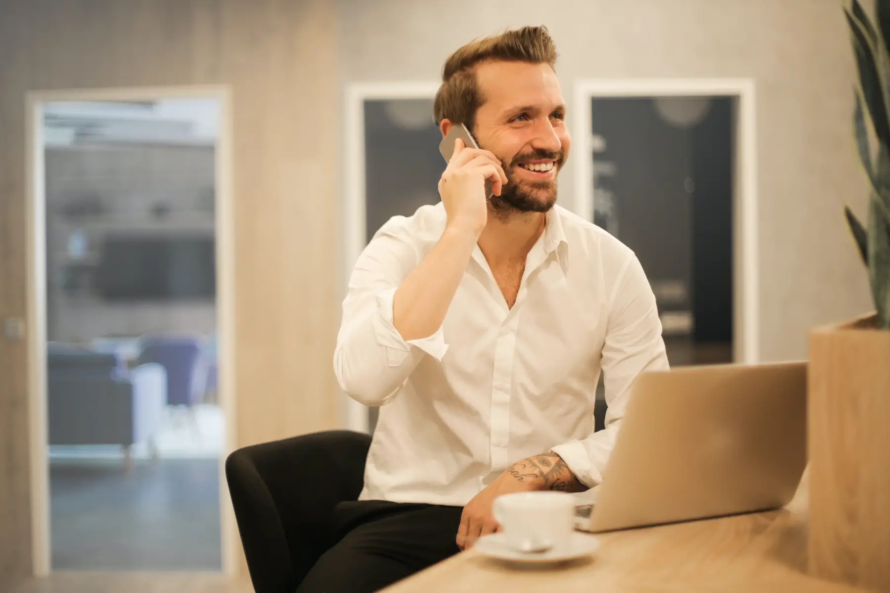 a man dressed professionally smiling while he chats on his mobile in an office