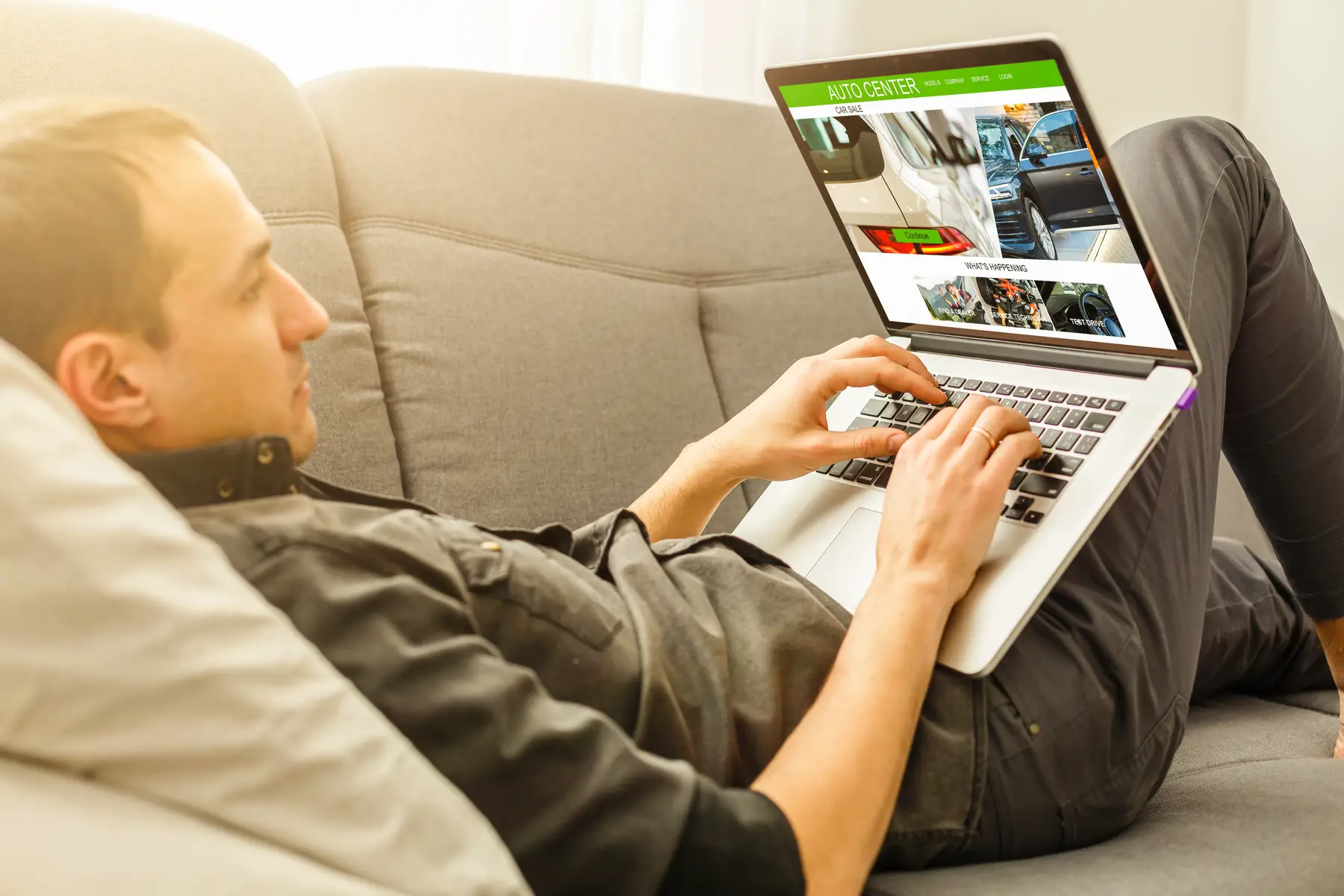 man on couch with laptop searching for cars online